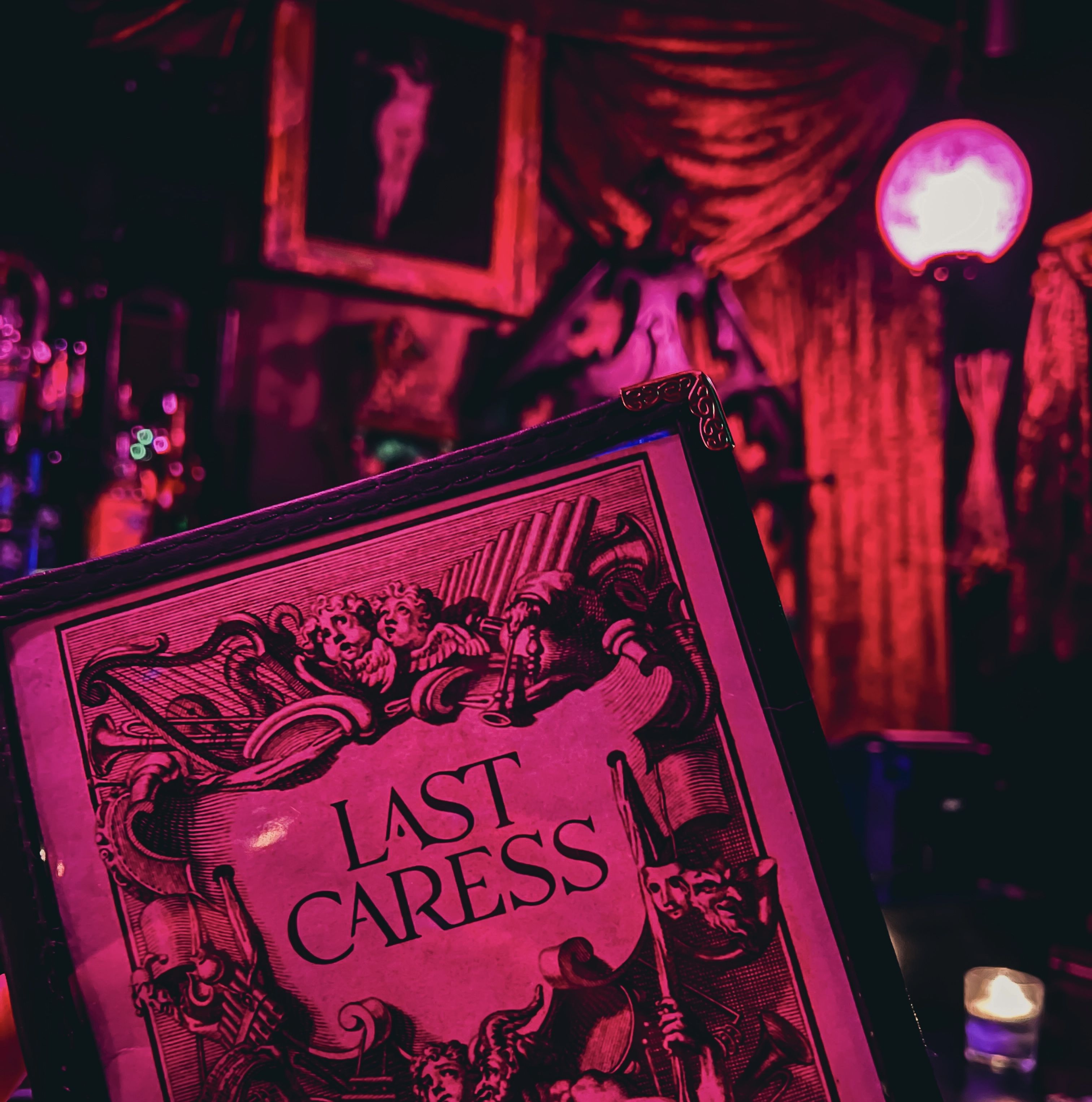 A photo of the Last Caress menu in pink mood lighting.