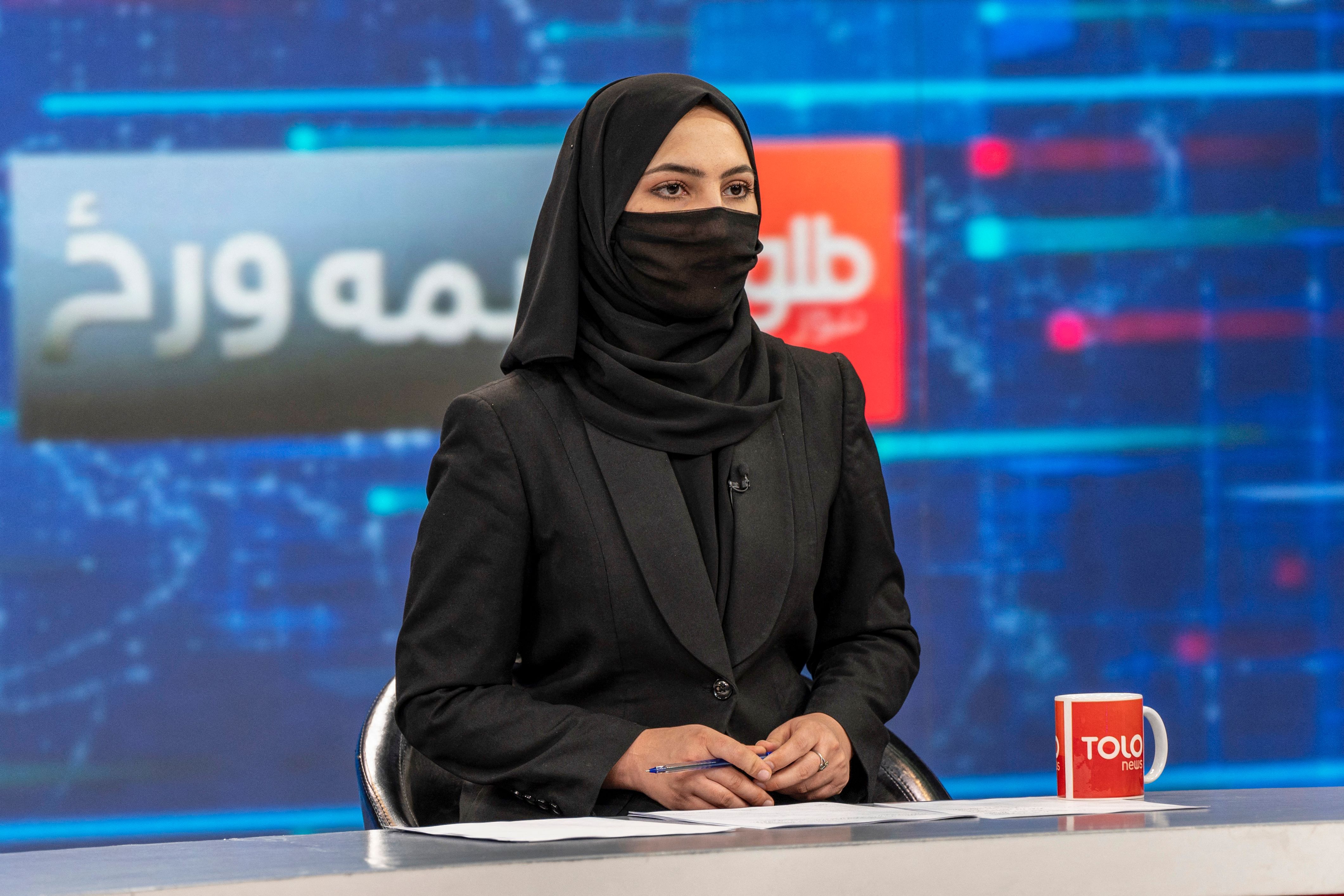 Female news presenter wearing hijab and face covering. 