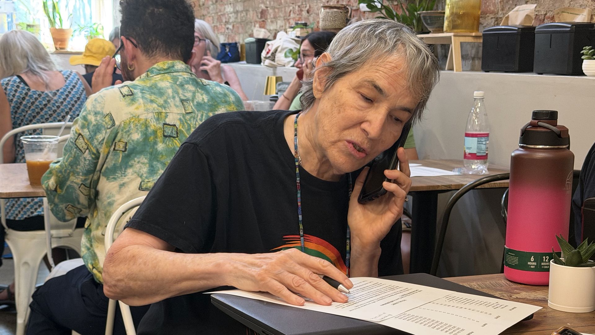 Thea Iberall of Hyde Park sits at a table calls senators about a bill to extend TPS for Haiti during a phone bank at Ula Cafe in Jamaica Plain on Aug. 4, 2026.