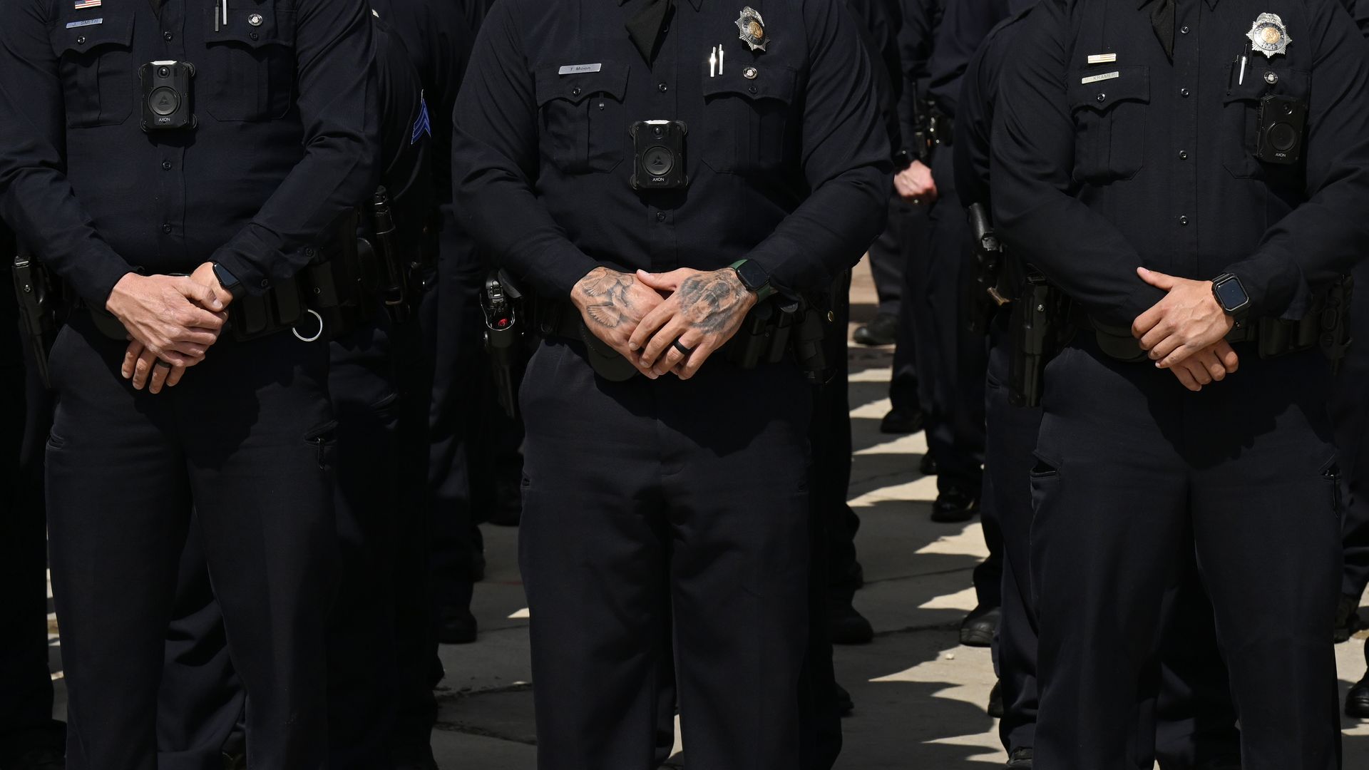 Several police officers stand solemnly side by side. 