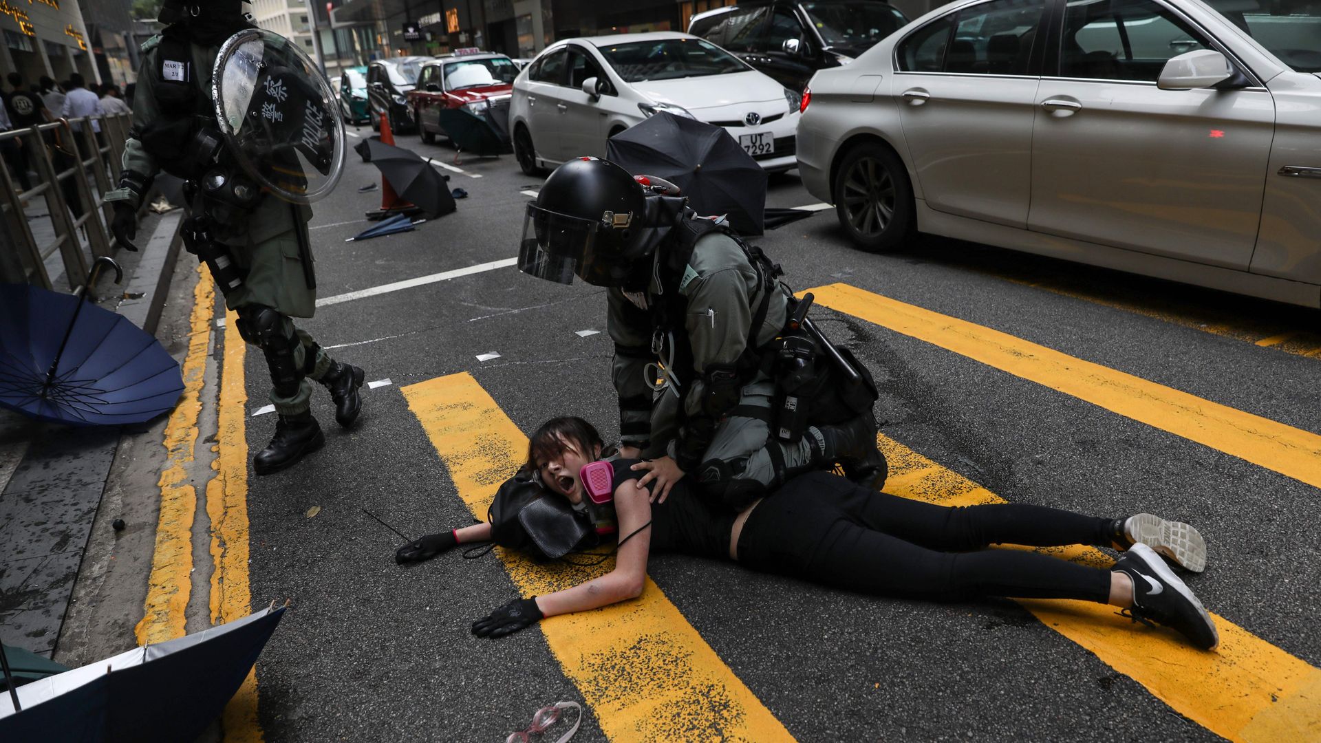 Police detain a woman during a flash mob to block roads in the Central district in Hong Kong on November 13