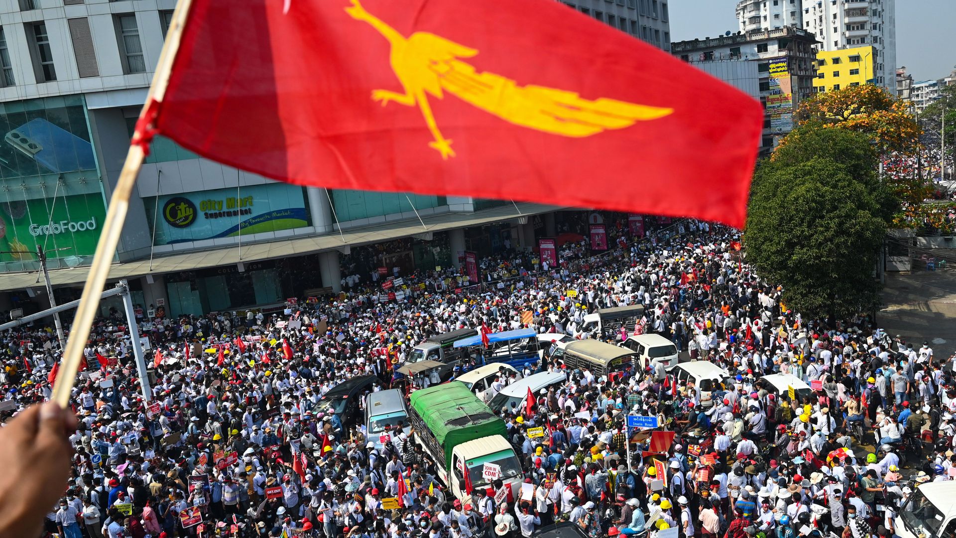  A protester waves the National League for Democracy (NLD) flag while others take part in a demonstration against the military coup in Yangon on February 22