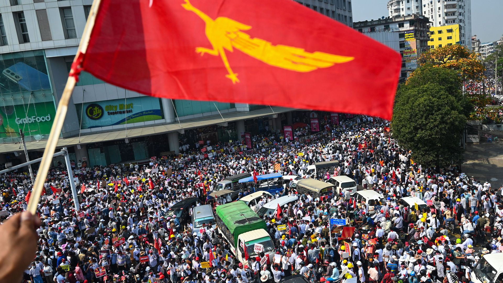 A protester waves the National League for Democracy (NLD) flag while others take part in a demonstration against the military coup in Yangon on February 22