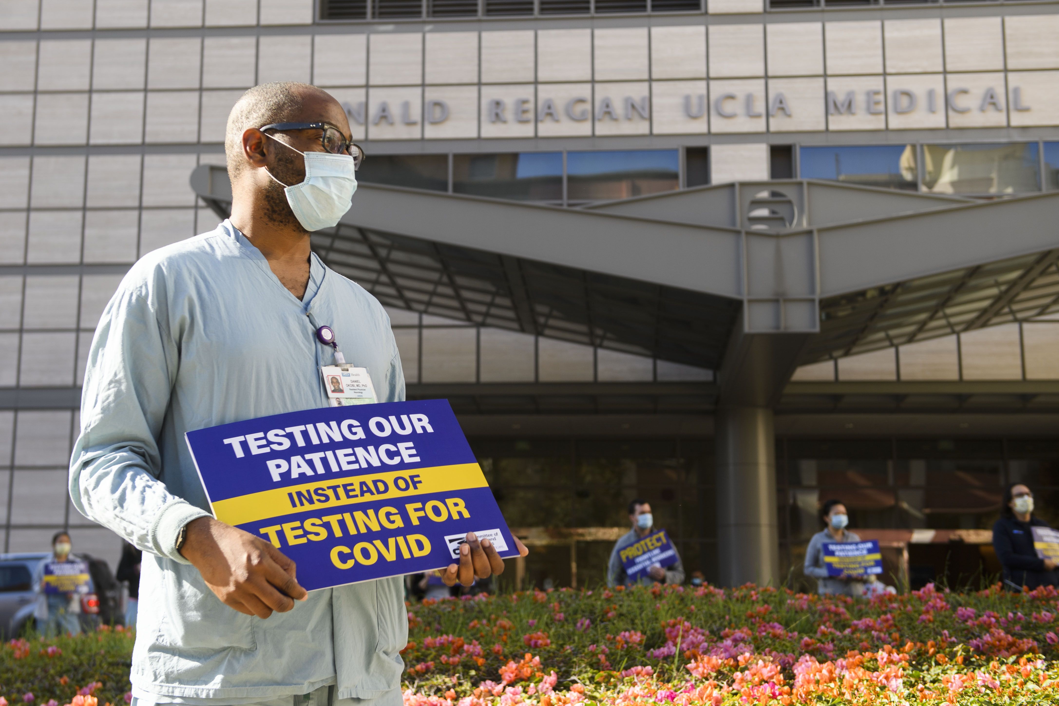 Healthcare workers wear face masks and carry signs in support of resident physicians, interns and fellows at UCLA Health