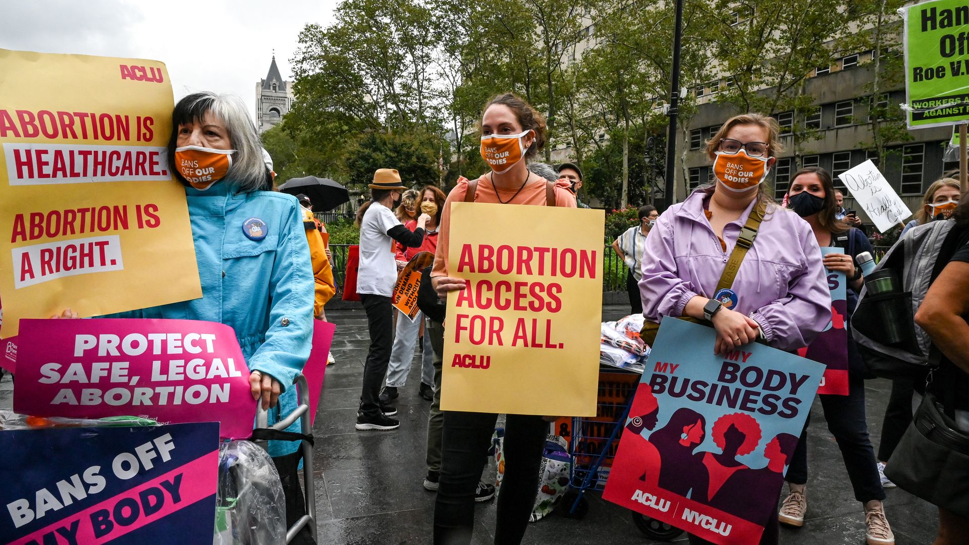 Picture of three women at a pro-choice protest holding signs that say "Abortion access for all."