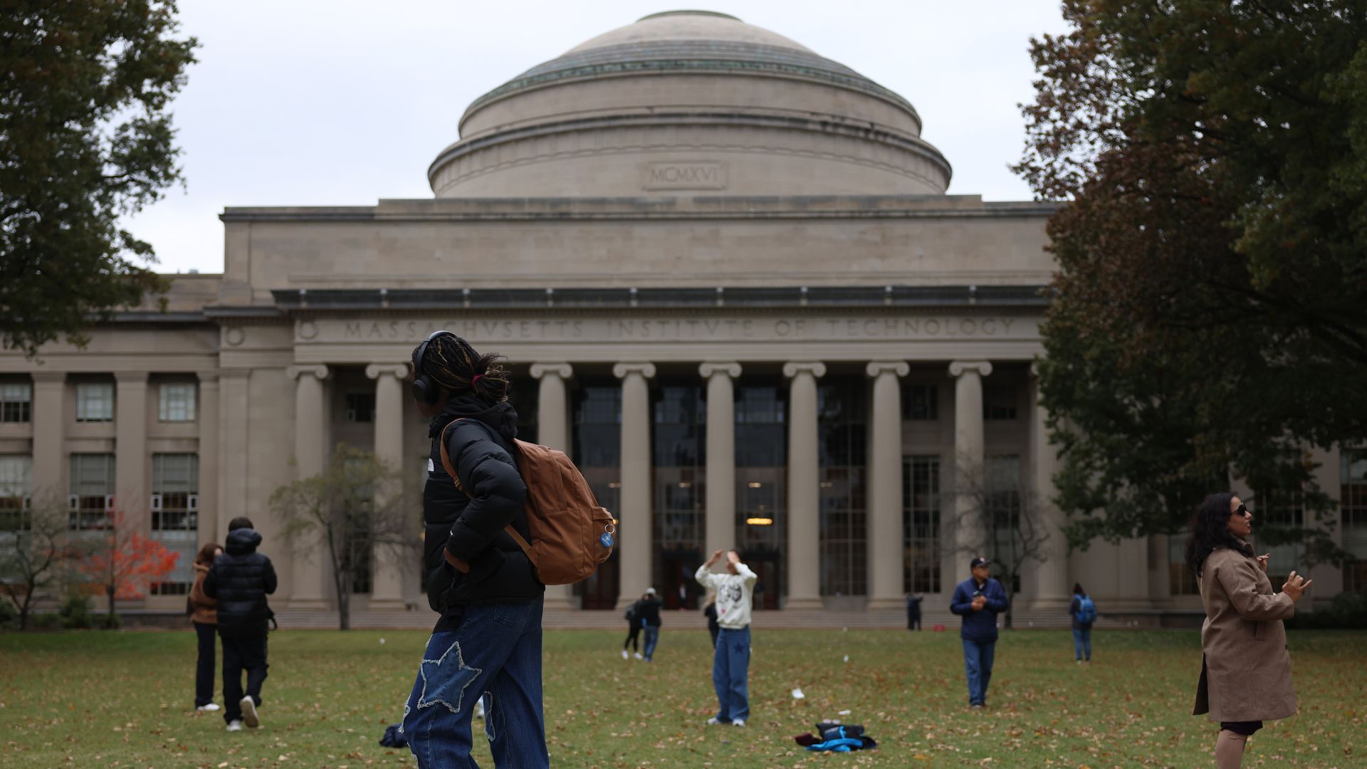 People gather outside MIT’s Great Dome in Cambridge, Massachusetts, with several holding up phones to take photos.