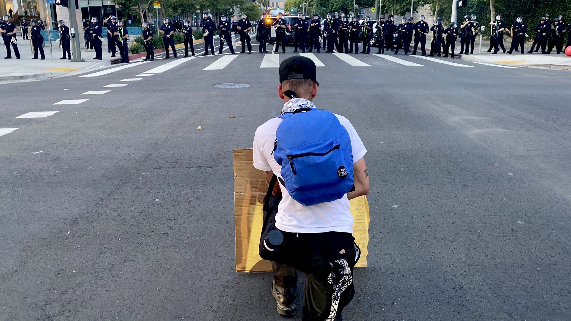 A protestor kneels in front of police