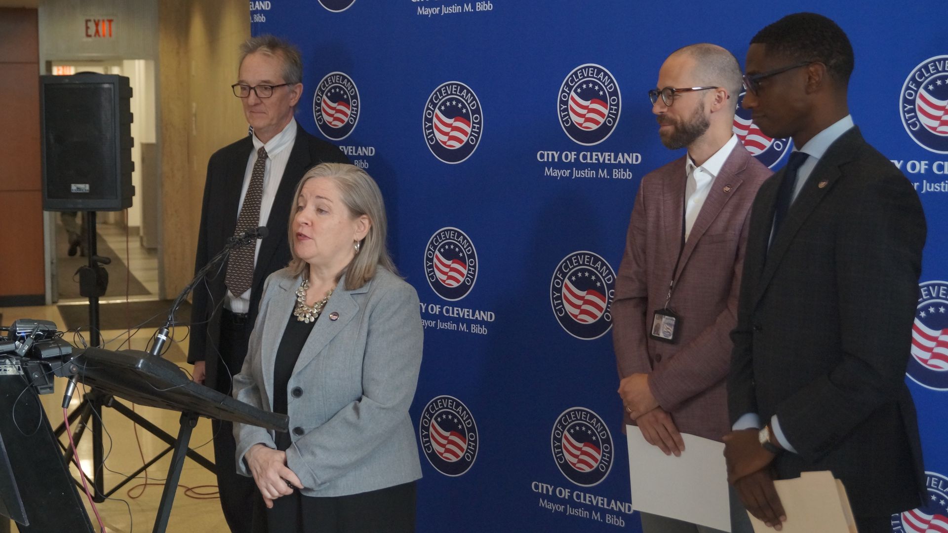 Cleveland director of building and housing at a lectern, flanked by three Cleveland officials, including Mayor Justin Bibb