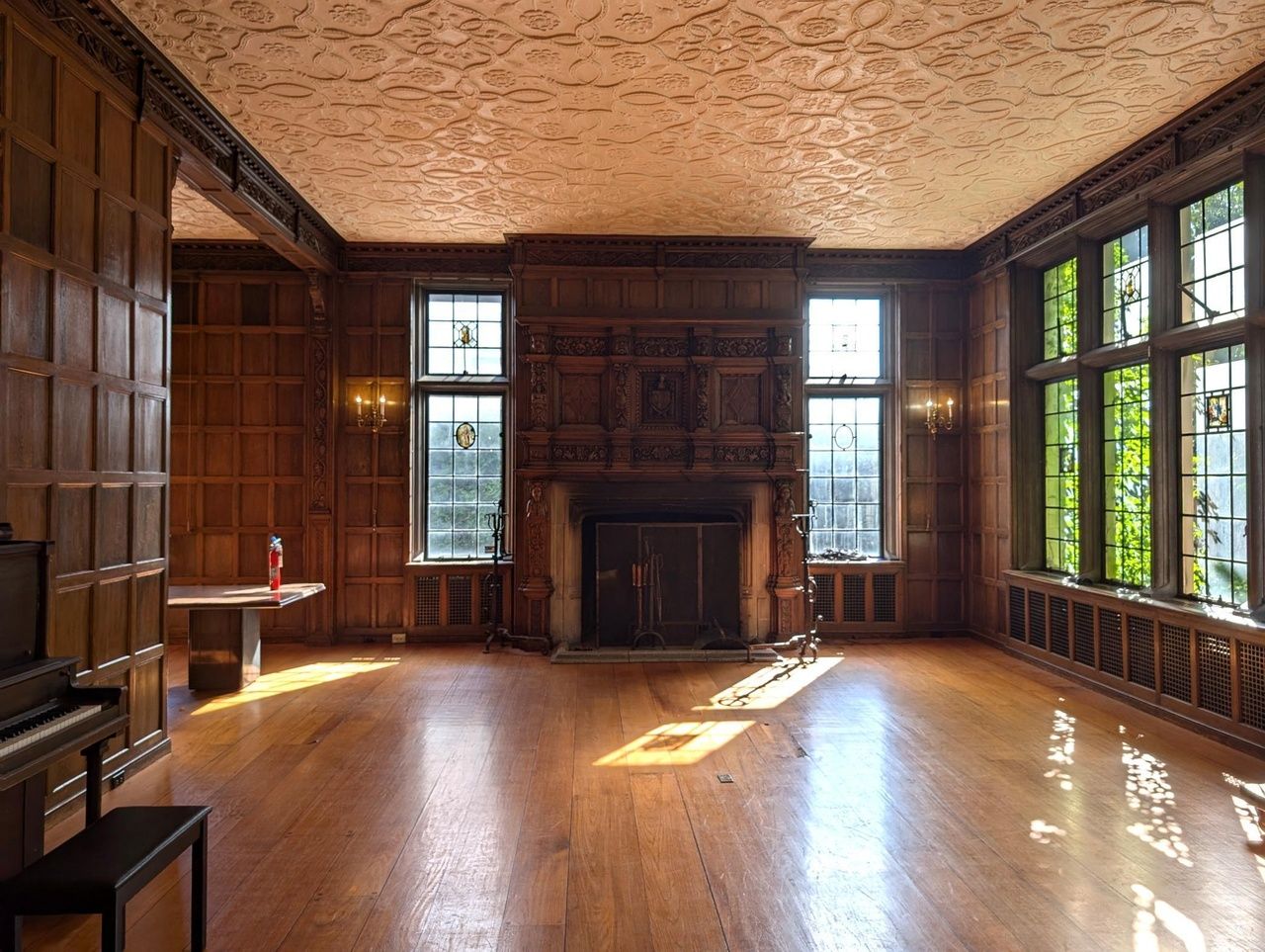 A spacious room with a wood fireplace and wood floors.