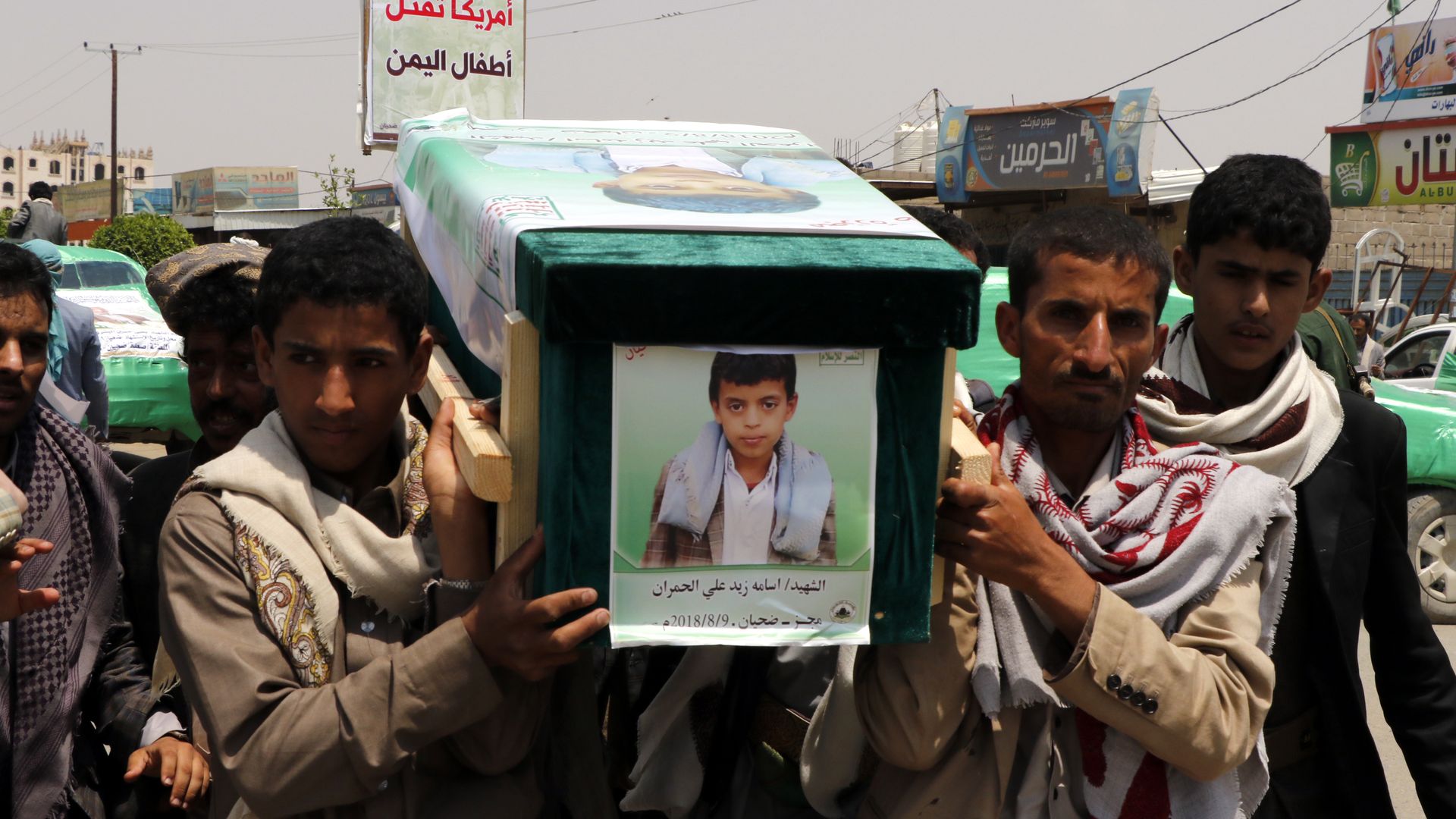 Men carry a coffin with the picture of a child on the front of it.