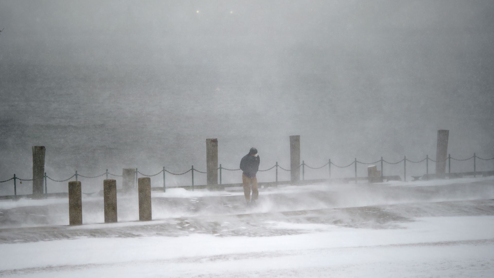 A pedestrian walks through a gust of wind along the waterfront in India Point Park in Providence, R.I., Saturday, Jan. 29, 2022.
