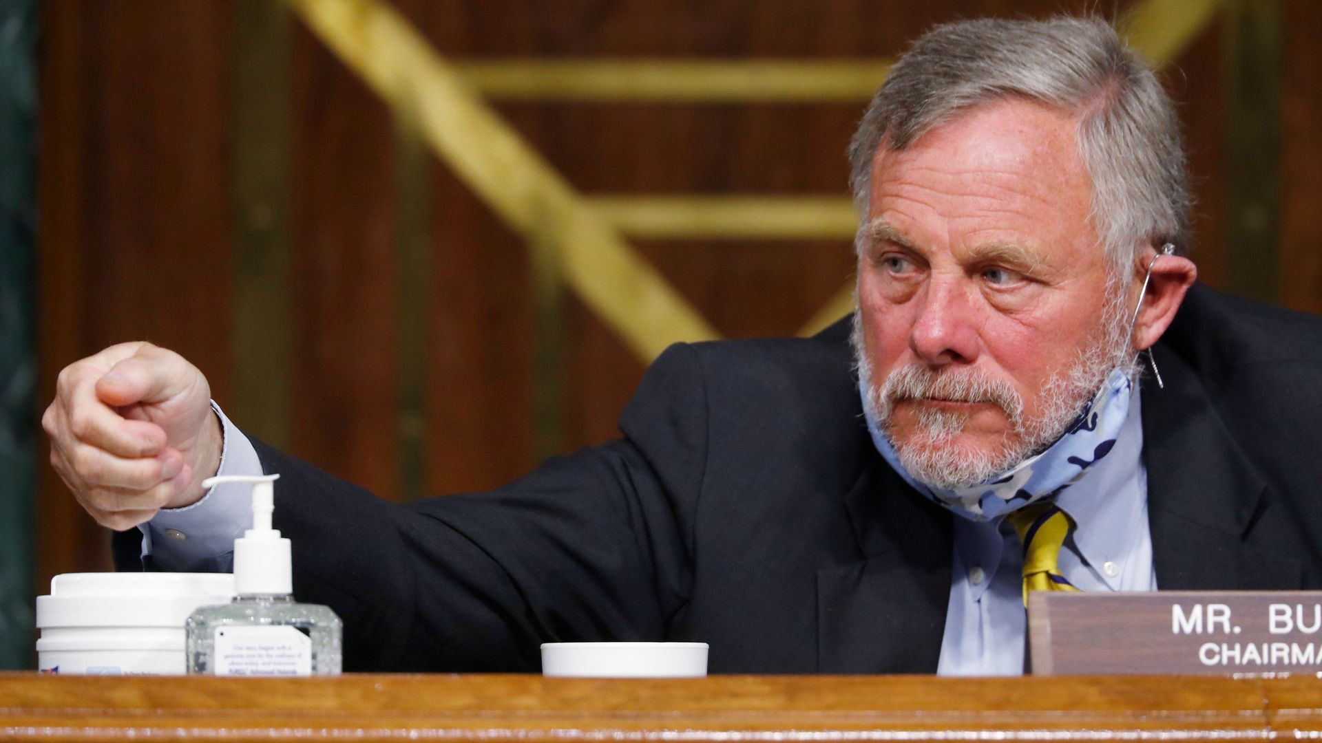 In this image, Burr reaches for hand sanitizer