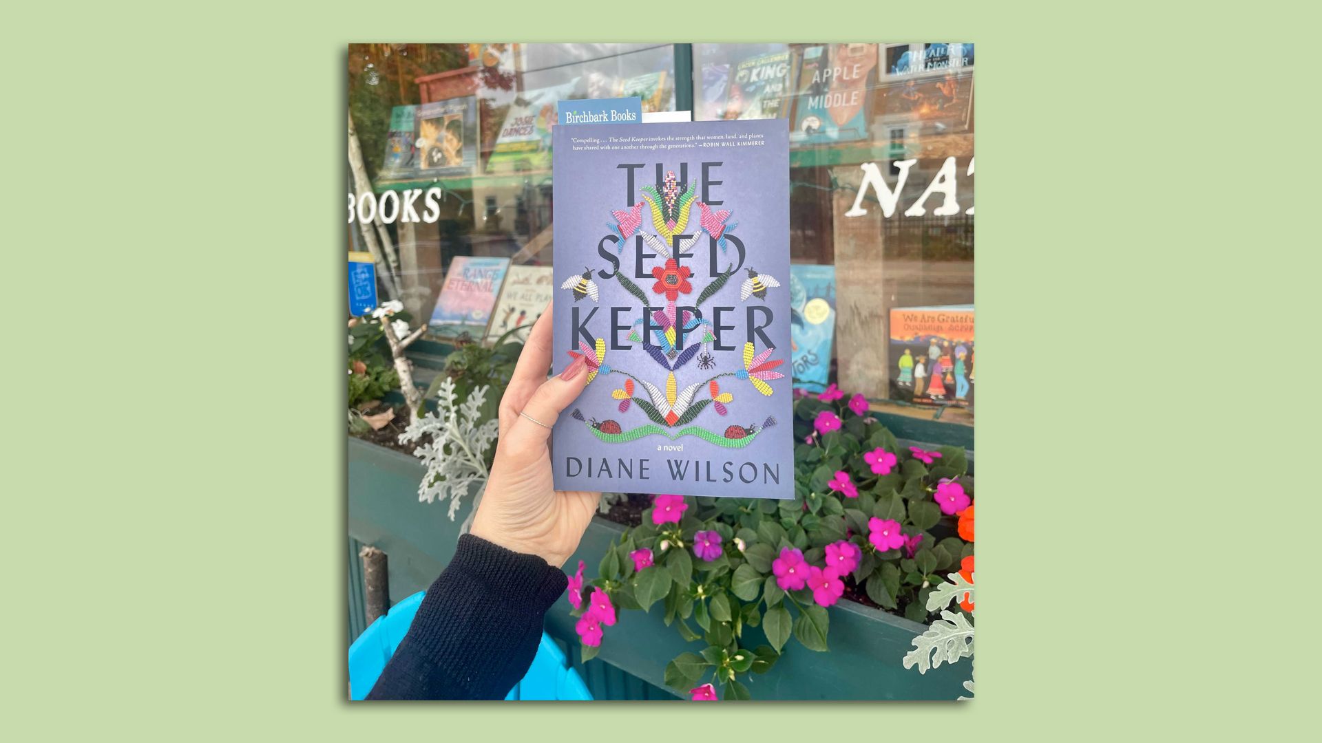 hand holding purple book in front of storefront