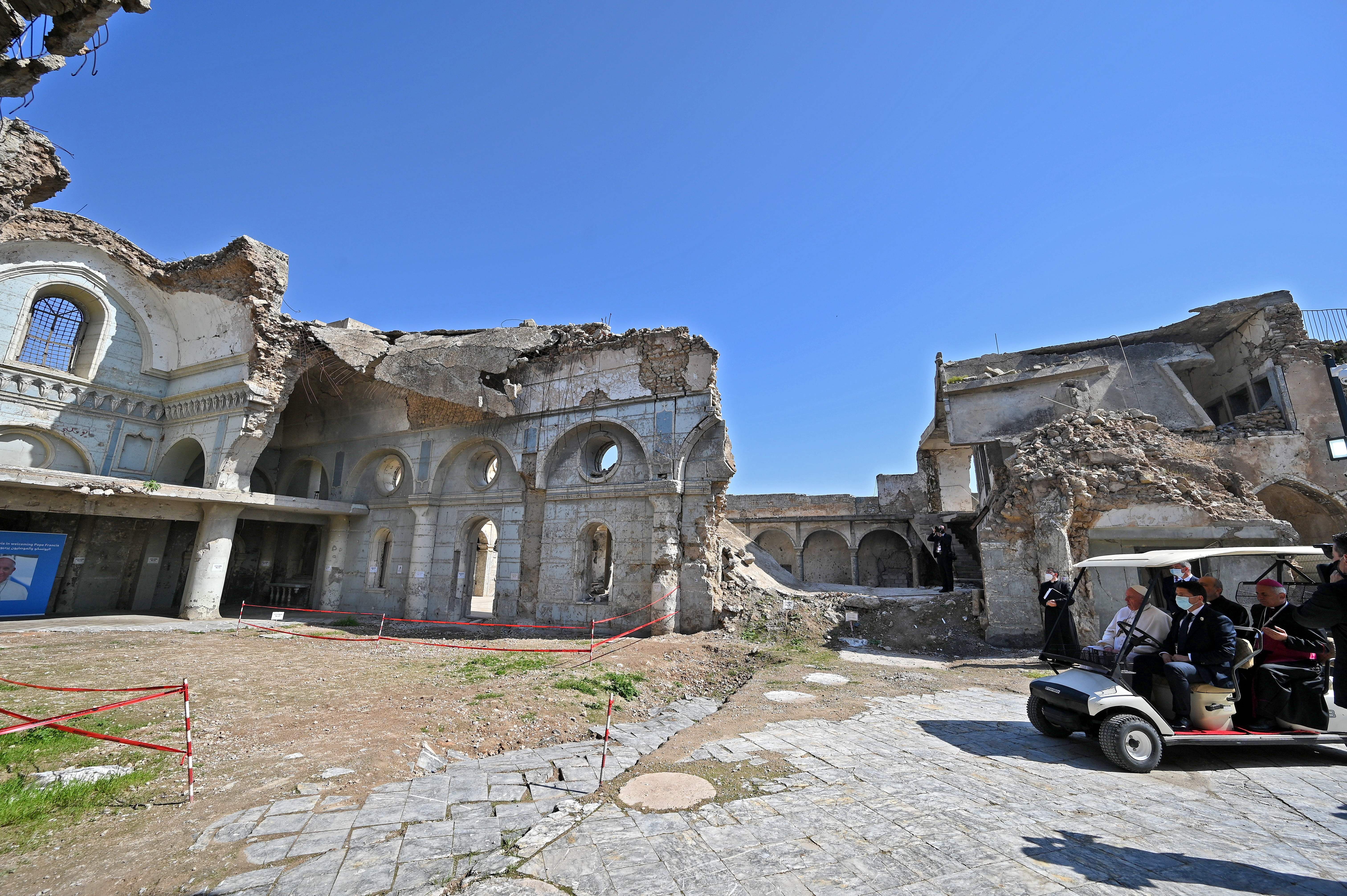 Pope Francis rides in a golf cart at the ruins of the Syriac Catholic Church of the Immaculate Conception (al-Tahira-l-Kubra), in the old city of Iraq's northern Mosul on March 7