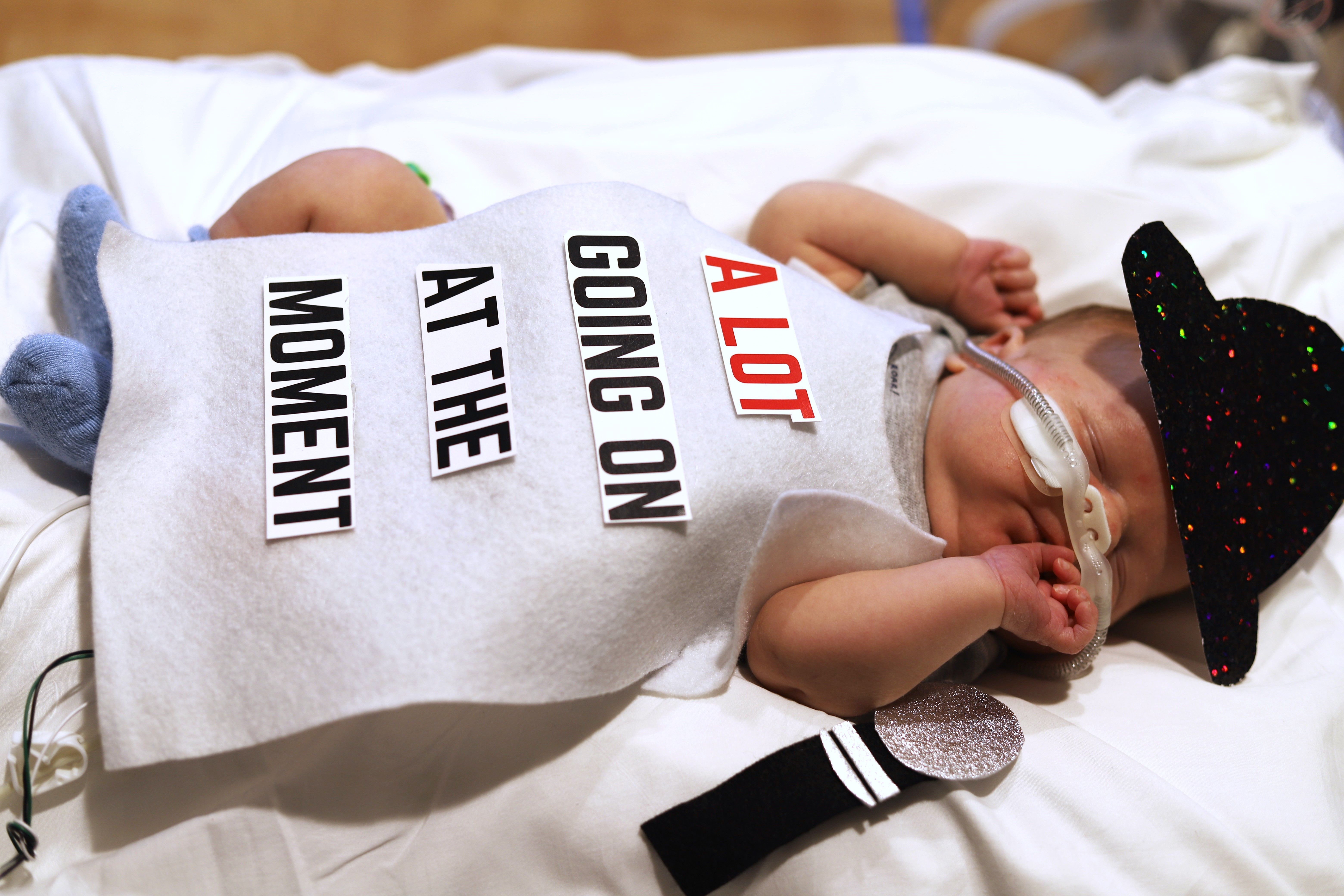 Image shows a baby with a shirt that says "A lot going on at the moment."