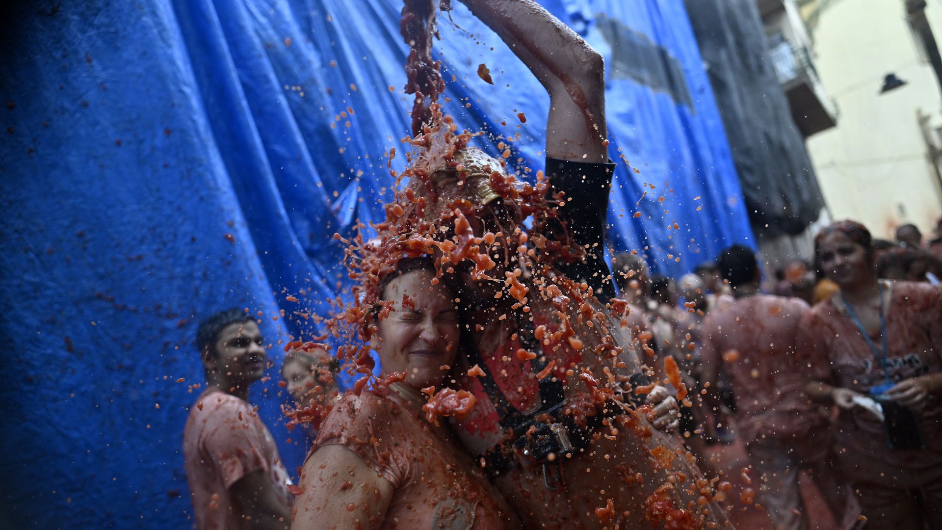 People celebrating a tomato festival in Spain dumping tomatoes on themselves.