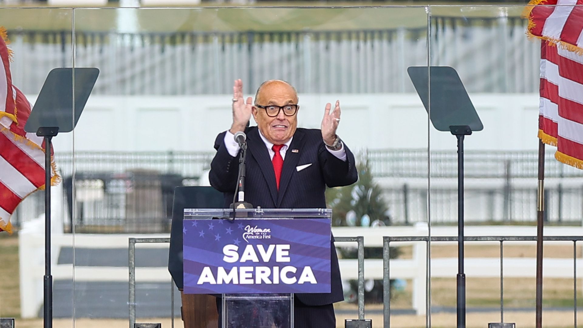 Rudy Giuliani stands at a podium with the sign "Save America" displayed