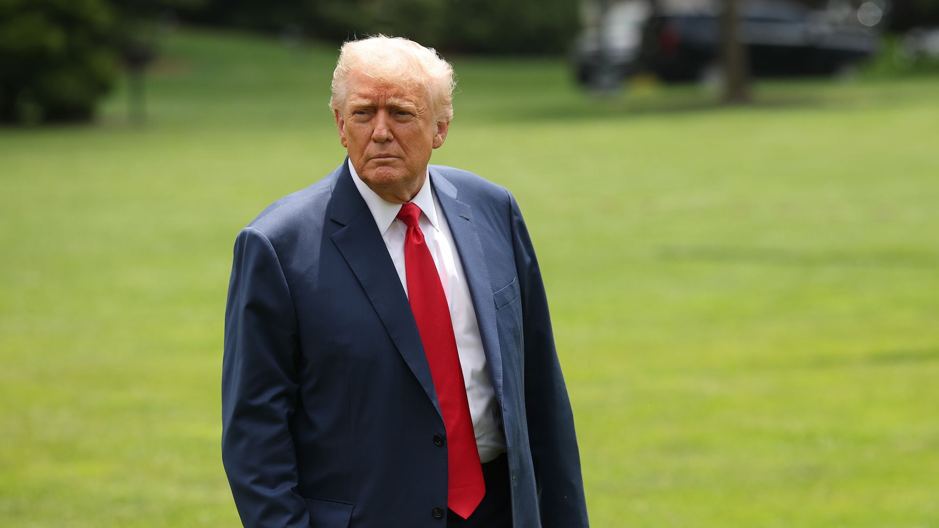 Man with red tie and blue suit on lawn
