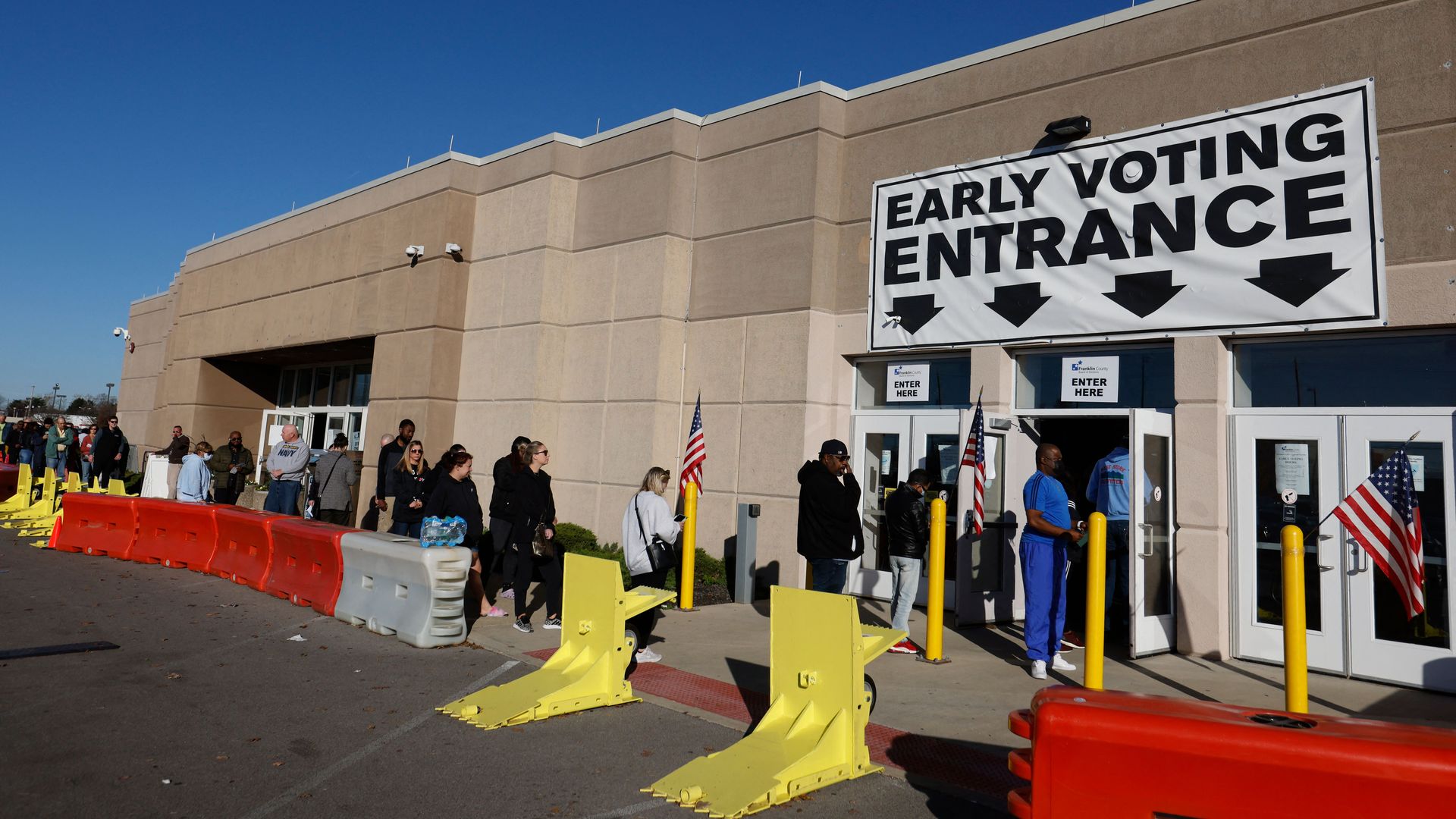 Voters waiting in line beneath a "Early Voting Entrance" sign. 