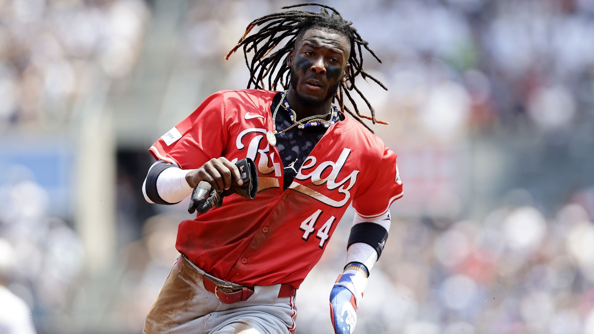 Elly De La Cruz of the Cincinnati Reds is seen running the bases while holding a batters glove.