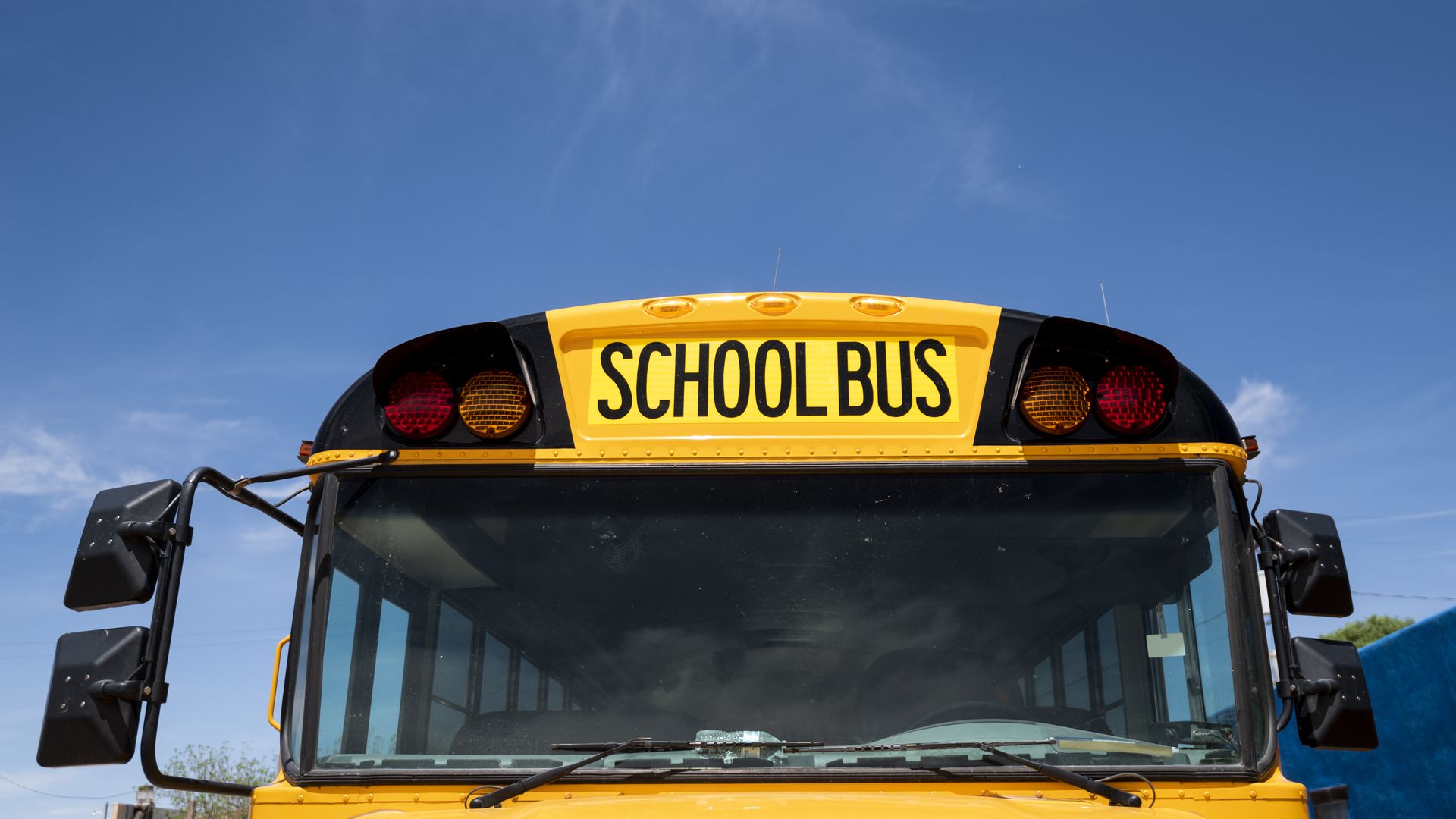The top of a yellow school bus parked with a blue sky in the background