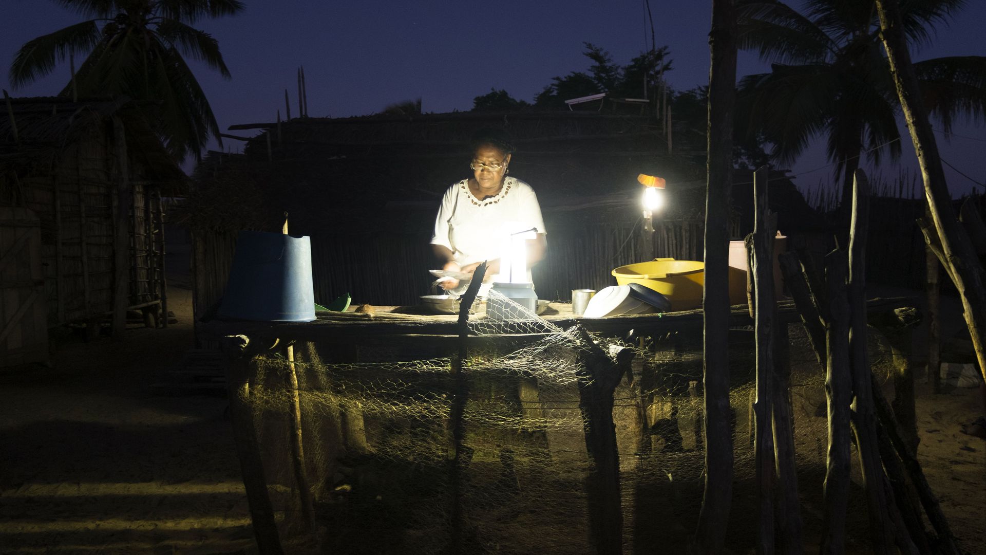 A woman in Madagascar working outside at night in lamplight