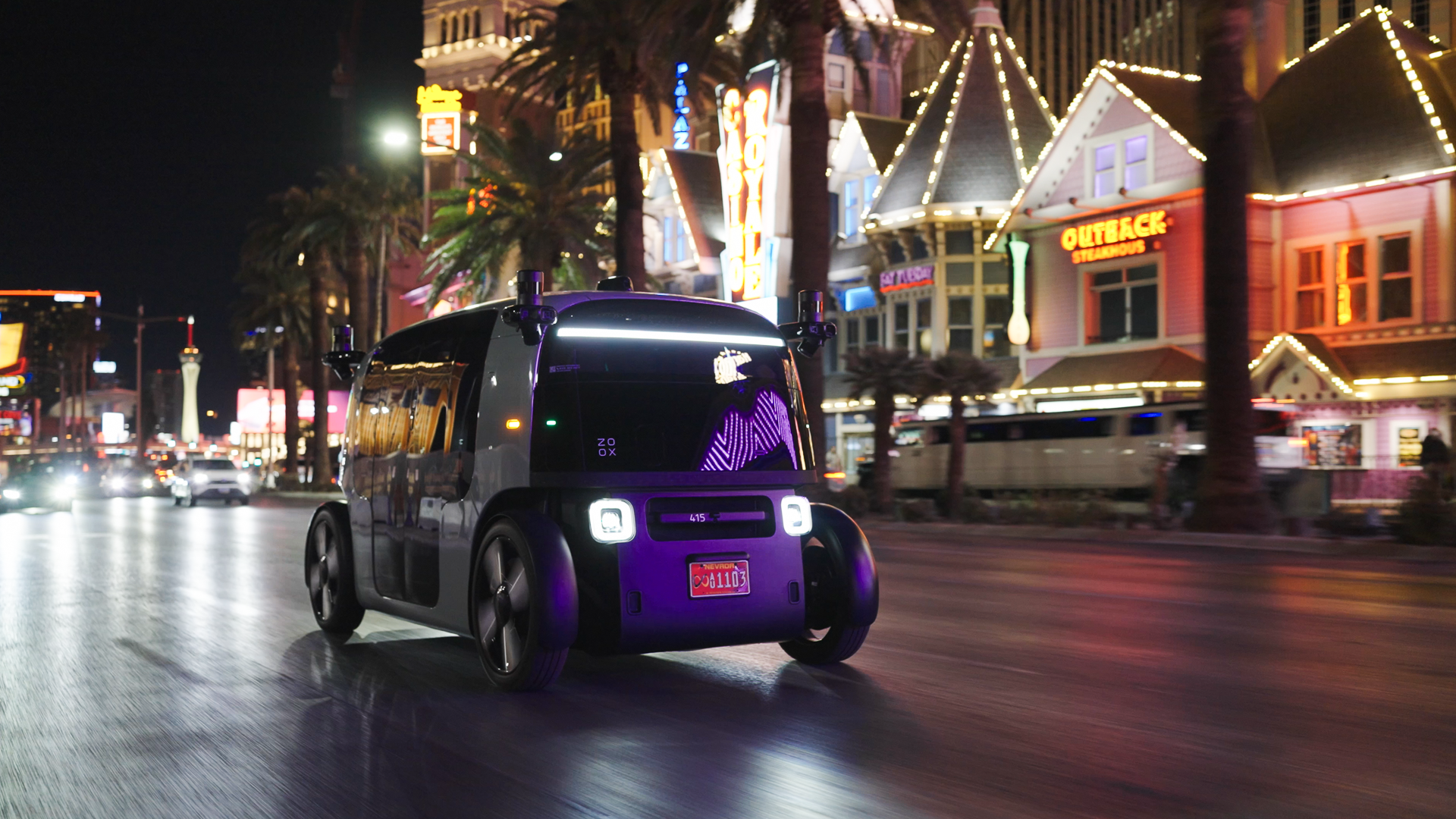 Purple Zoox robotaxi drives at night on the Las Vegas Strip. 