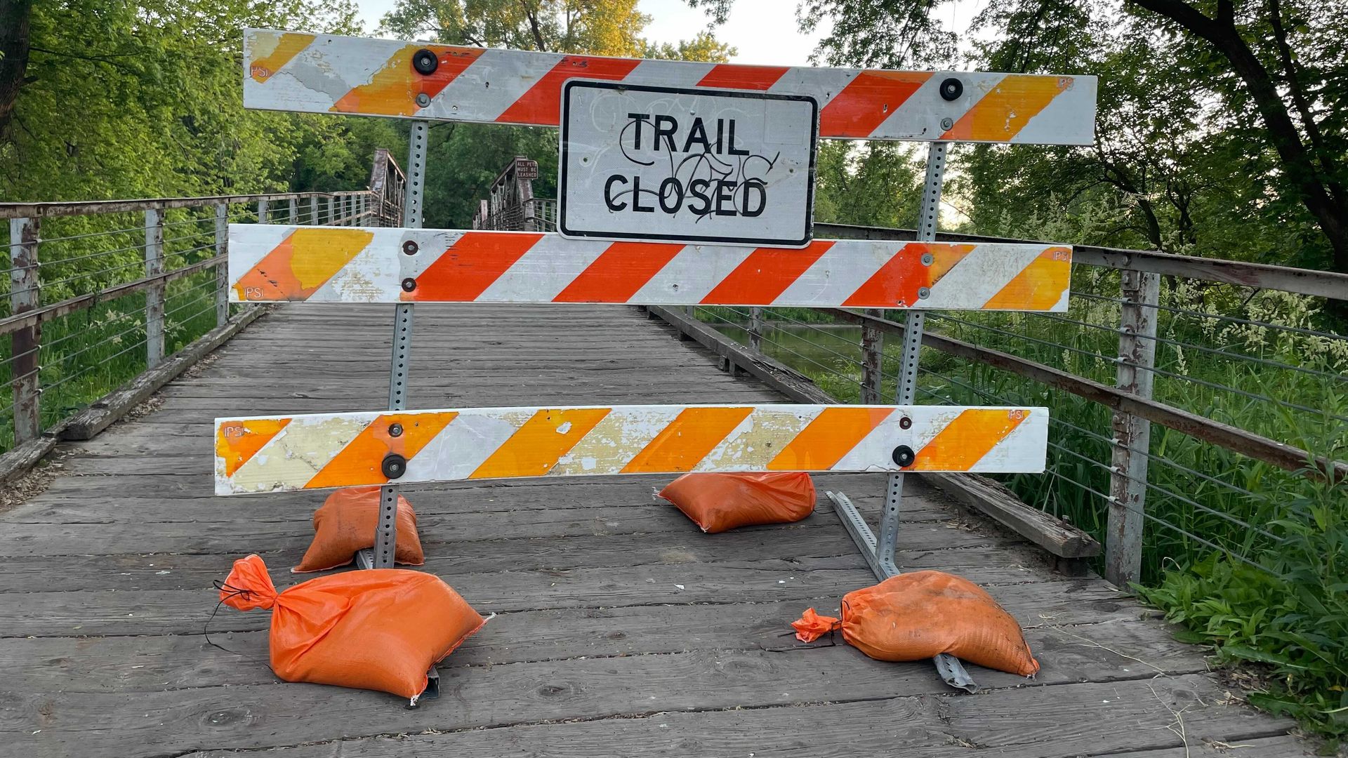 A trail closed sign stands on a bridge