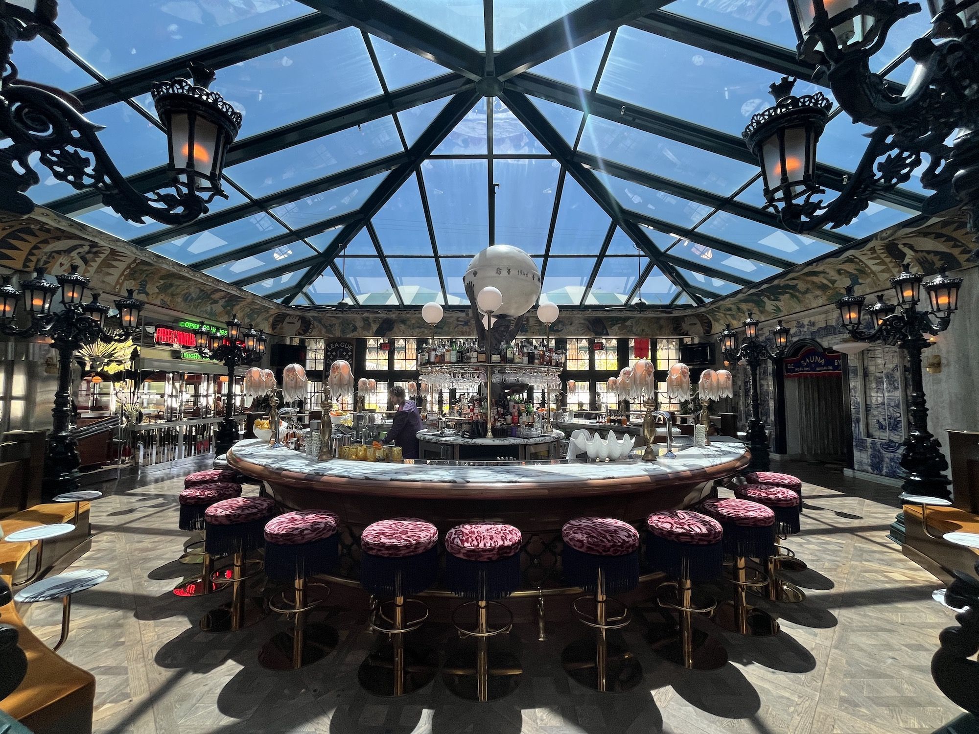 A large circular cocktail hotel bar with lavish decor and a glass ceiling.