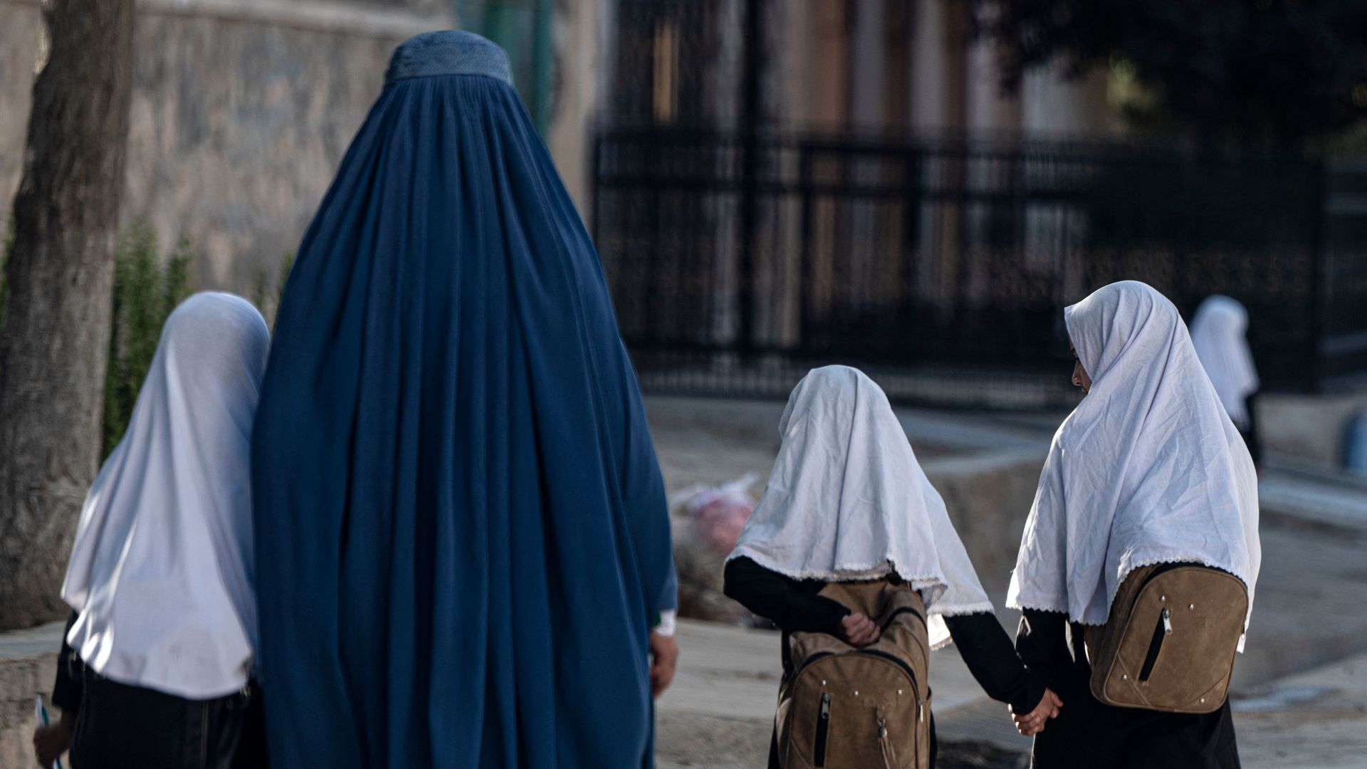 An Afghan woman walks with schoolgirls going to their primary school in Kabul.