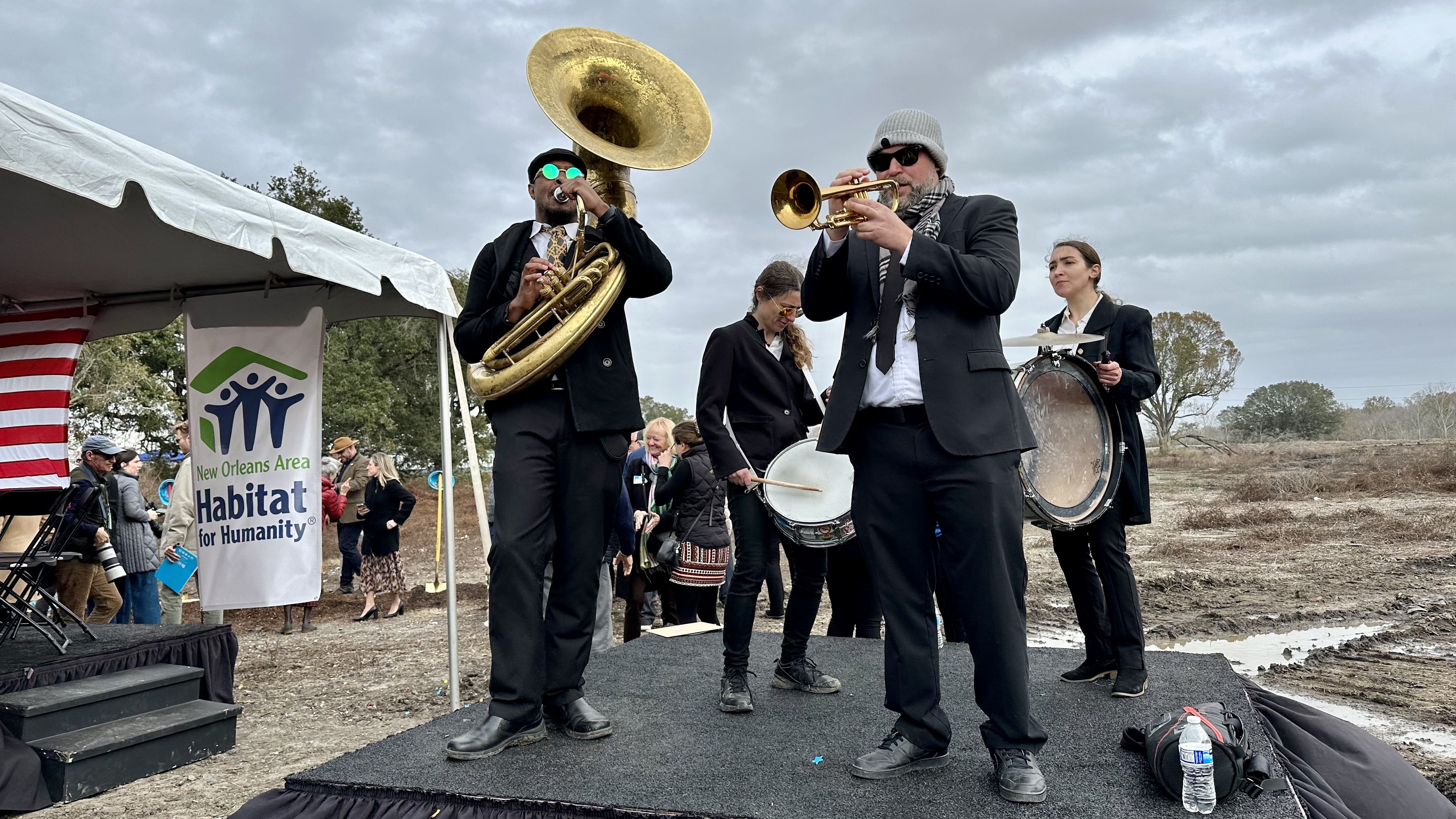 Photo shows musicians playing on a stage in front of a construction site