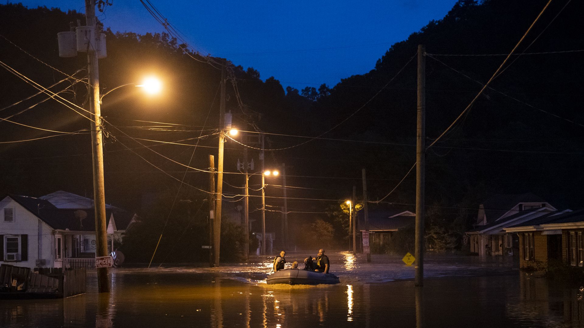 Search and rescue workers navigate a flooded street by boat