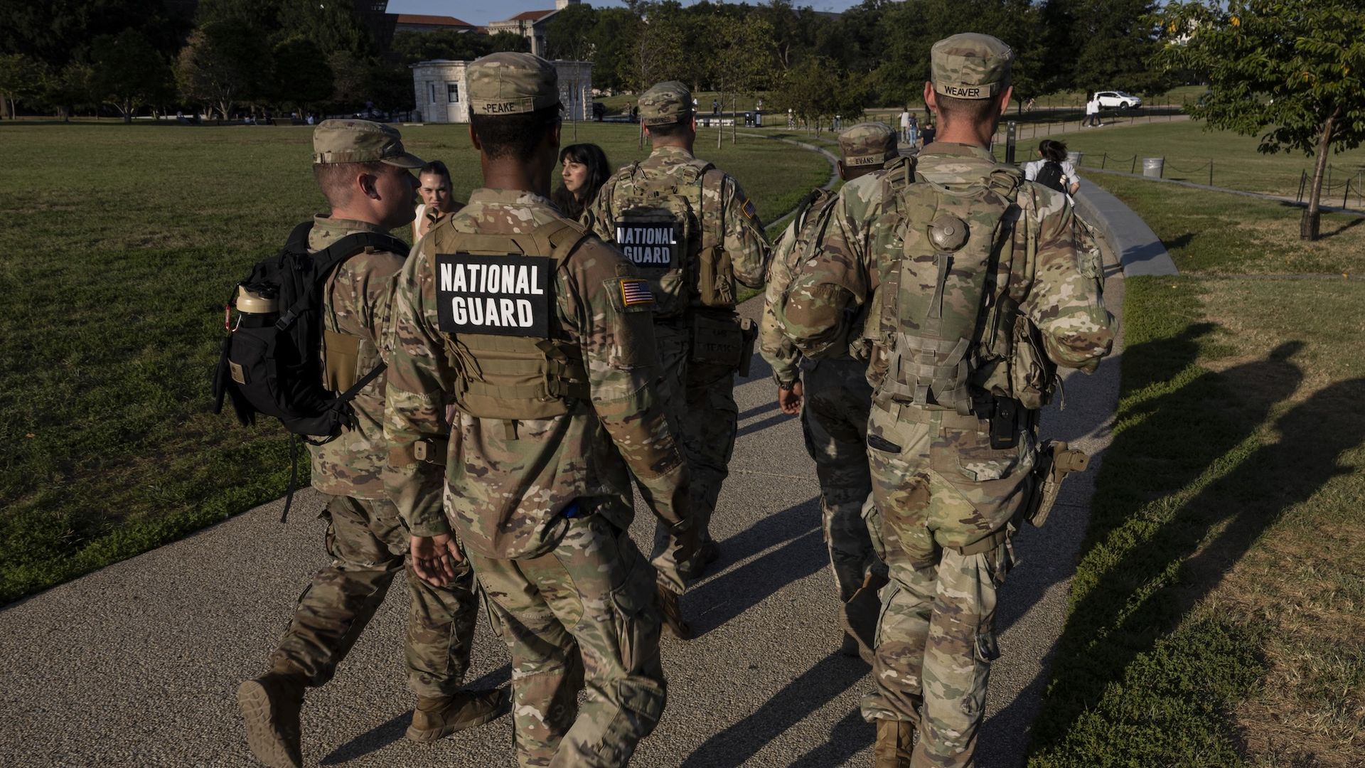 Back of members of the National Guard carrying sidearms patrol the National Mall in Washington, D.C.