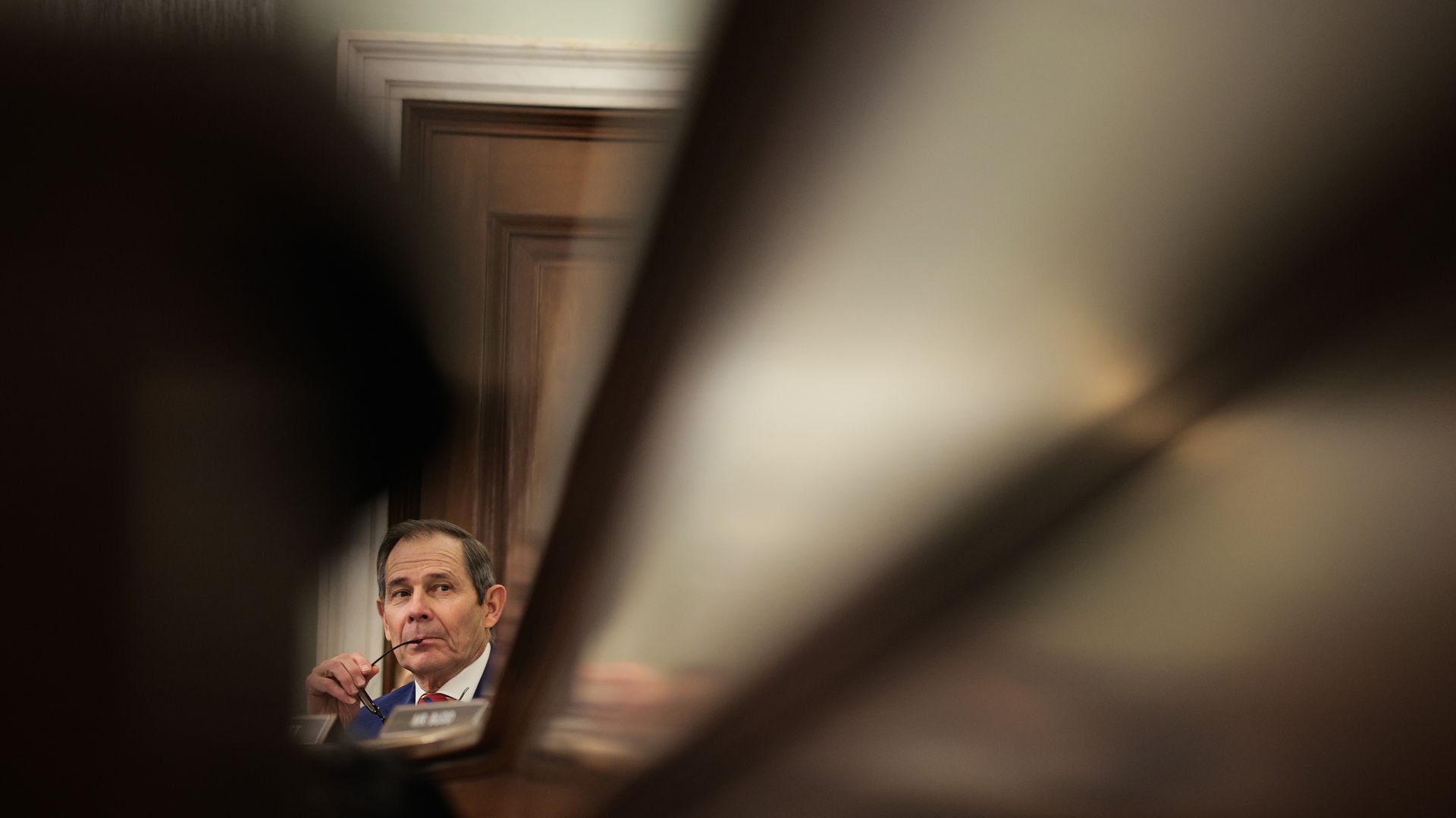 John Curtis appears between blurry furniture beams