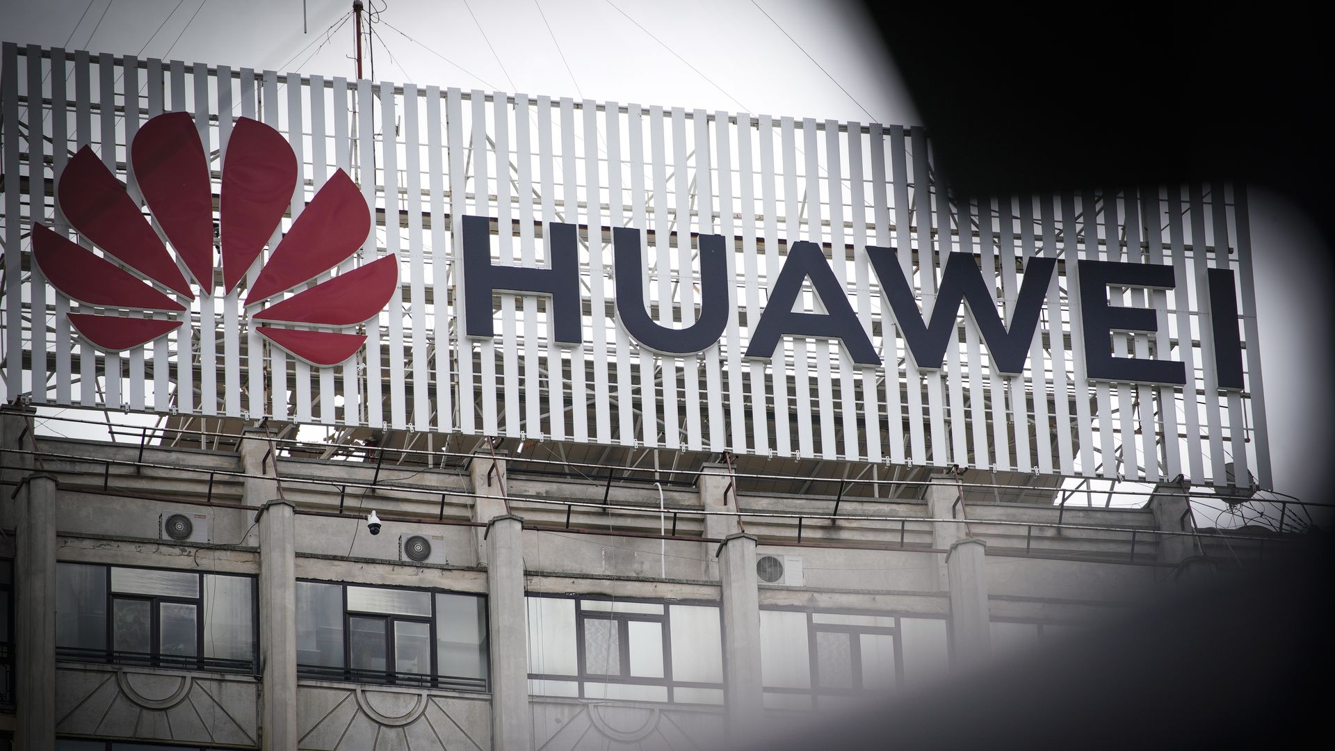In this image, the Huawek logo is seen on the side of a building on a foggy day.