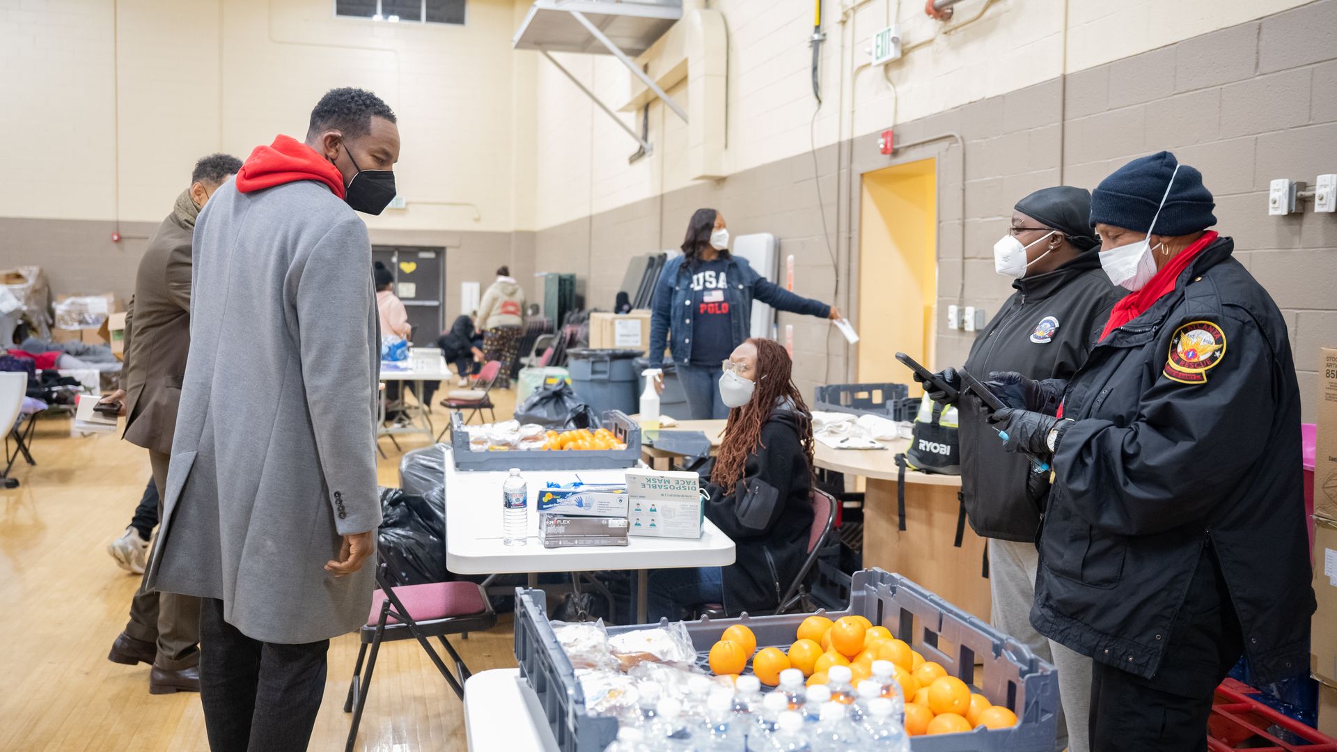 Mayor Andre Dickens looks at a table covered with oranges and bottles of water at a warming center for unsheltered people