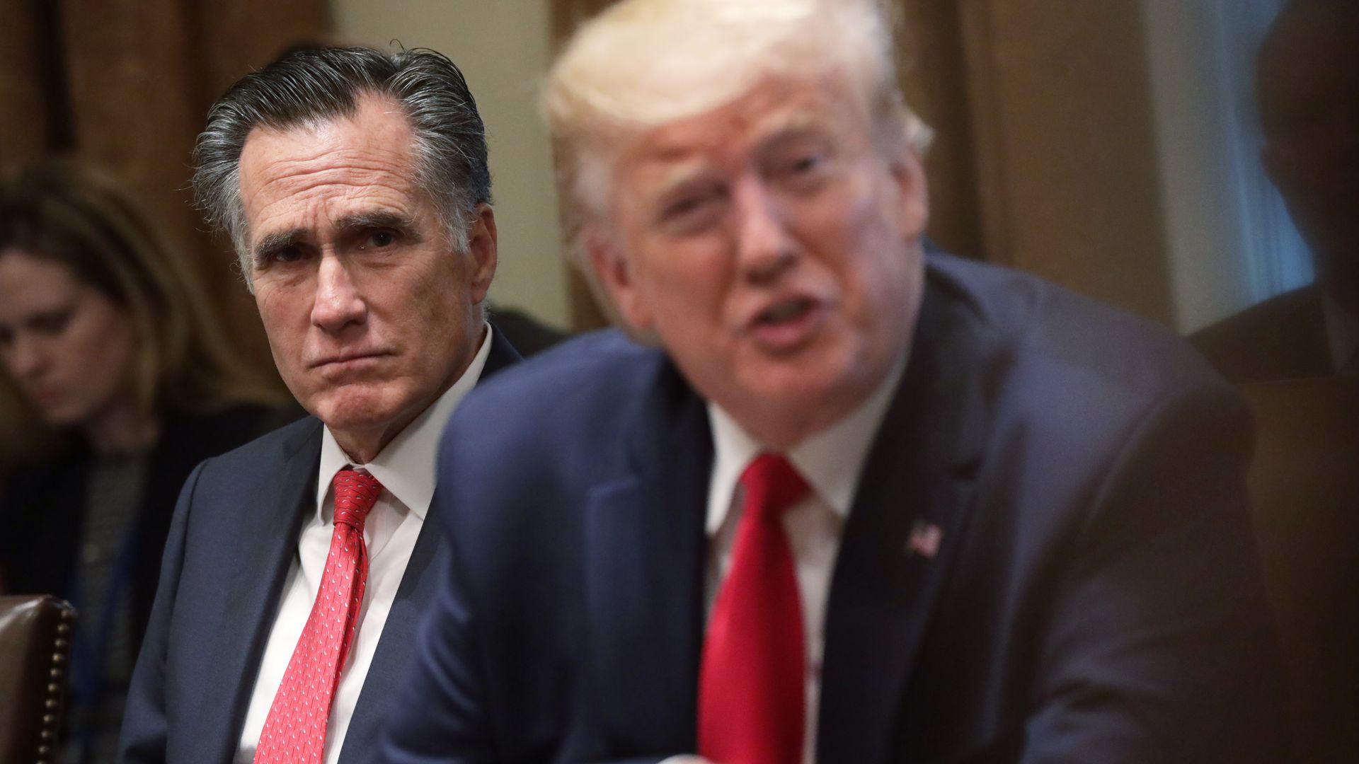 Mitt Romney sitting behind Trump