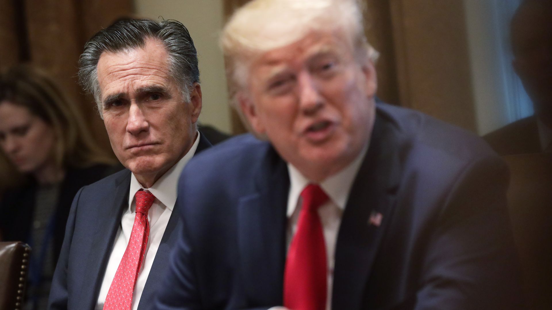 Mitt Romney sitting behind Trump
