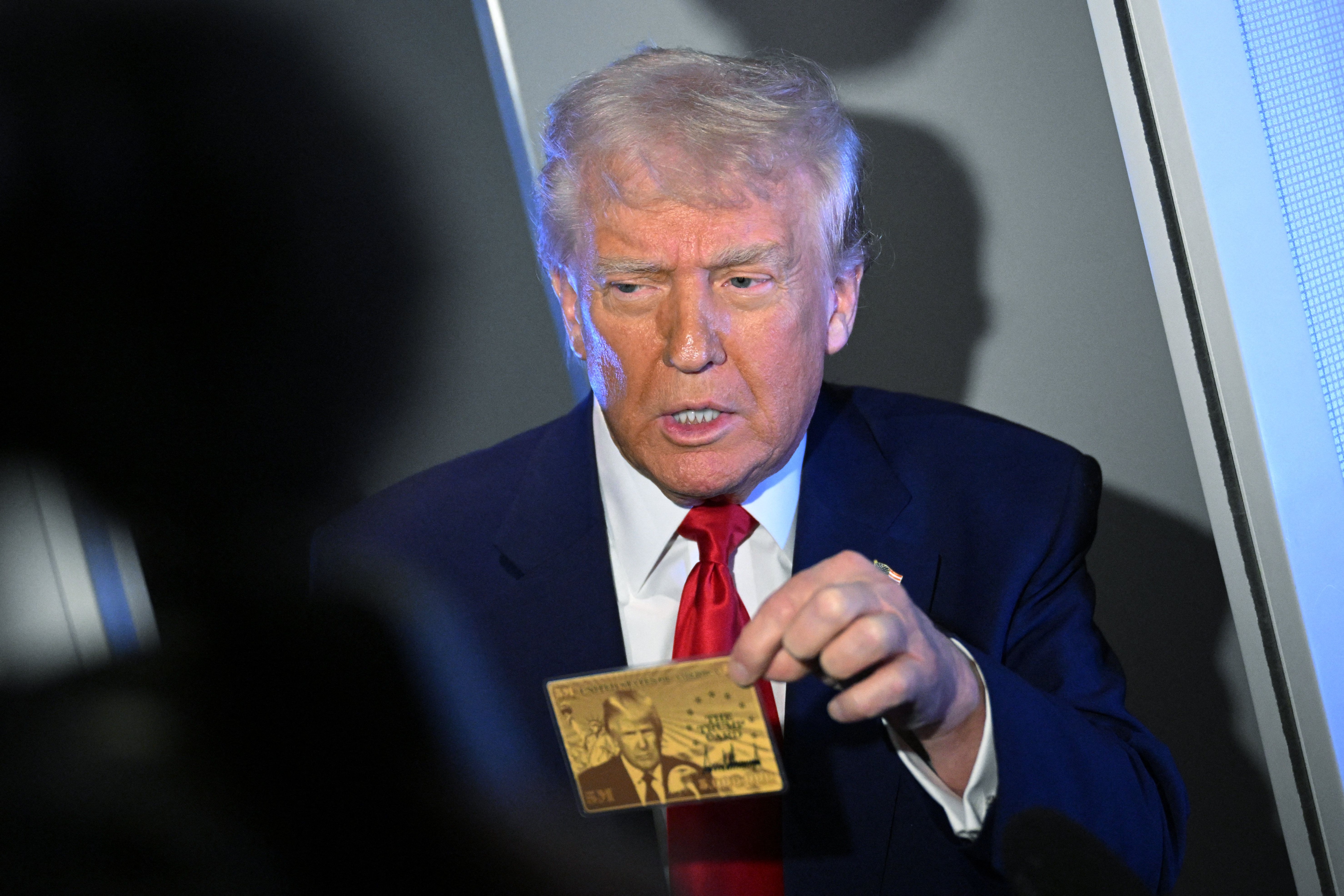 President Trump shows reporters on Air Force One a sample of the $5 million permanent residency "gold card."