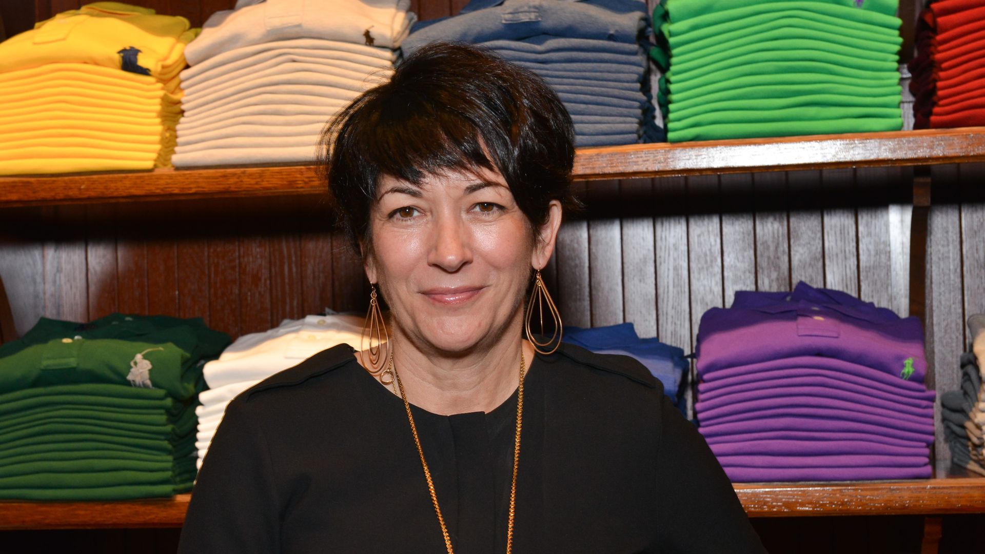 Maxwell standing in front of racks of clothing, wearing a black shirt and gold jewelry