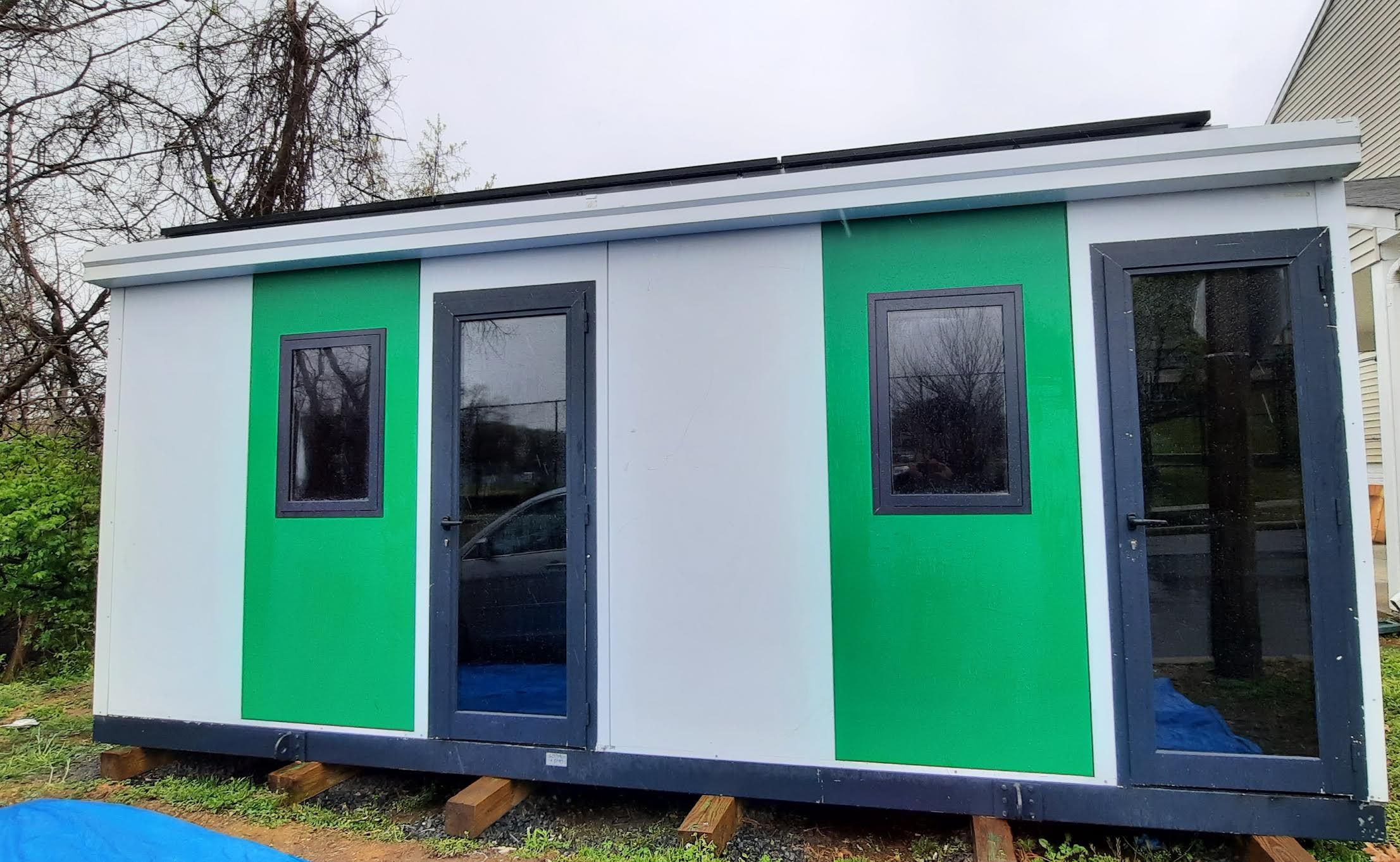 A modular home with green doors that's used to grow mushrooms