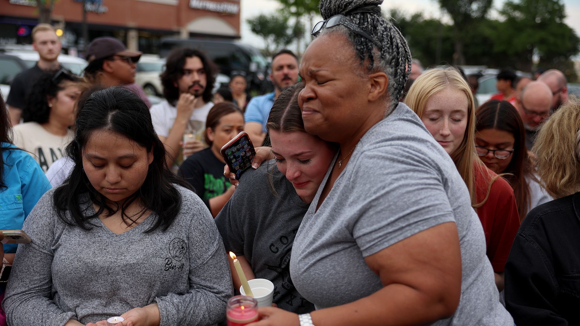 Women hug during a vigil at a memorial next to the Allen Premium Outlets on May 7, 2023 in Allen, Texas.
