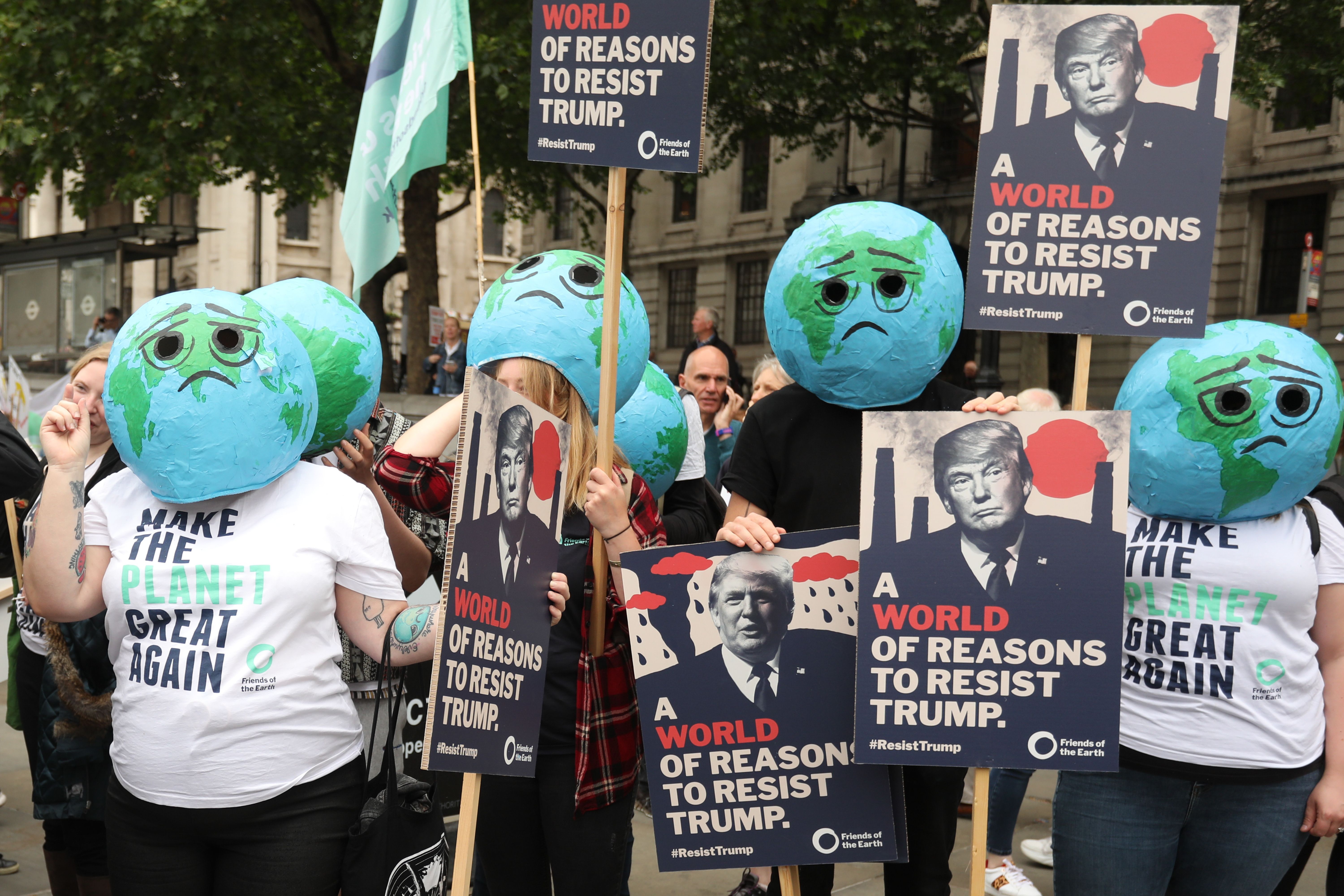 Climate and anti-Trump protesters pose with placards during a demonstration against the State Visit of US President Donald Trump in central London on June 4.