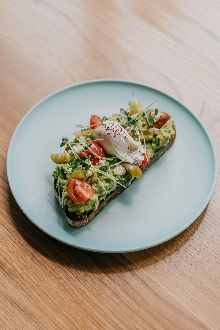 Avocado toast with poached egg, chopped tomatoes and sprouts.