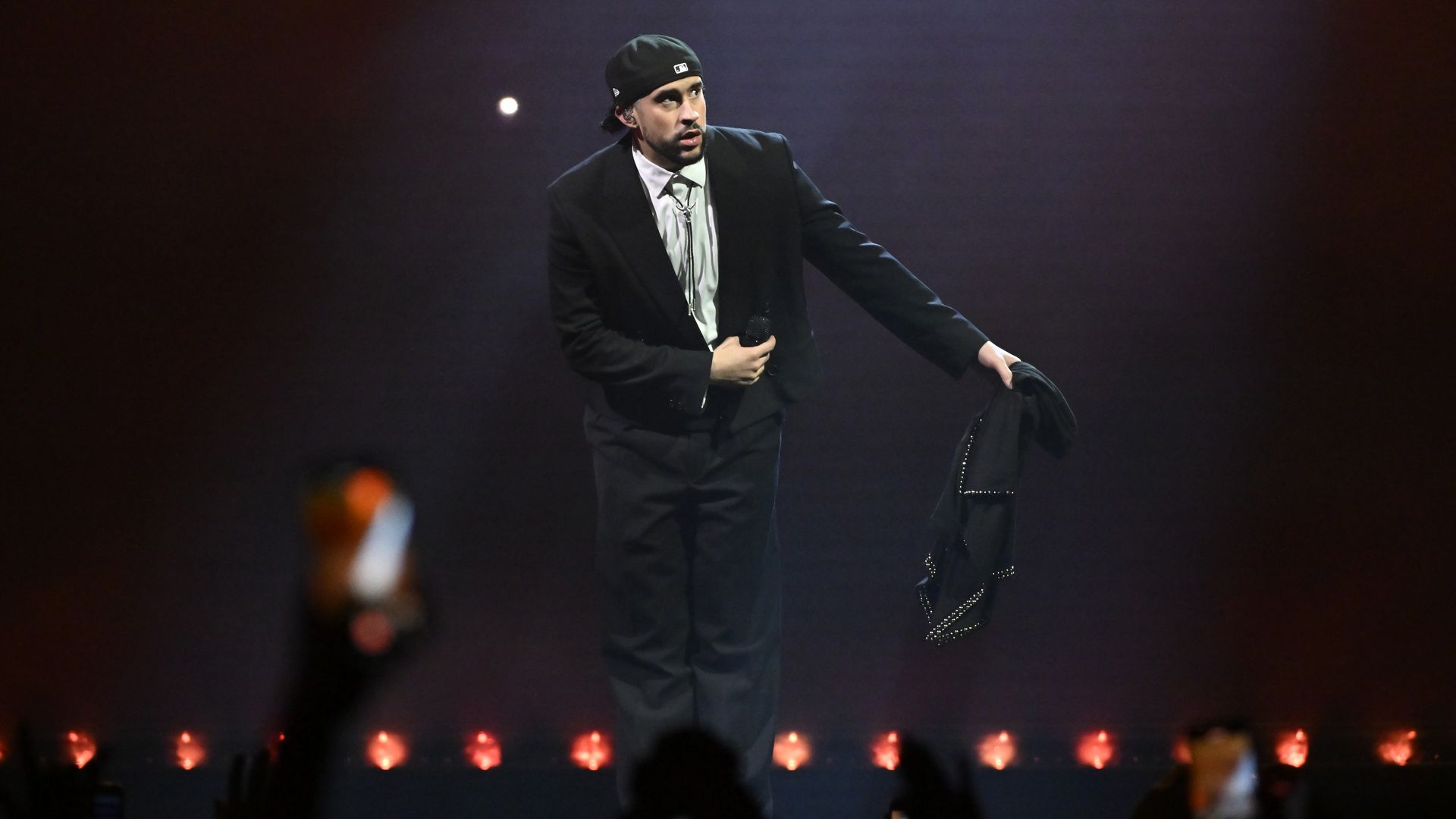 Bad Bunny performs on stage wearing mostly black.