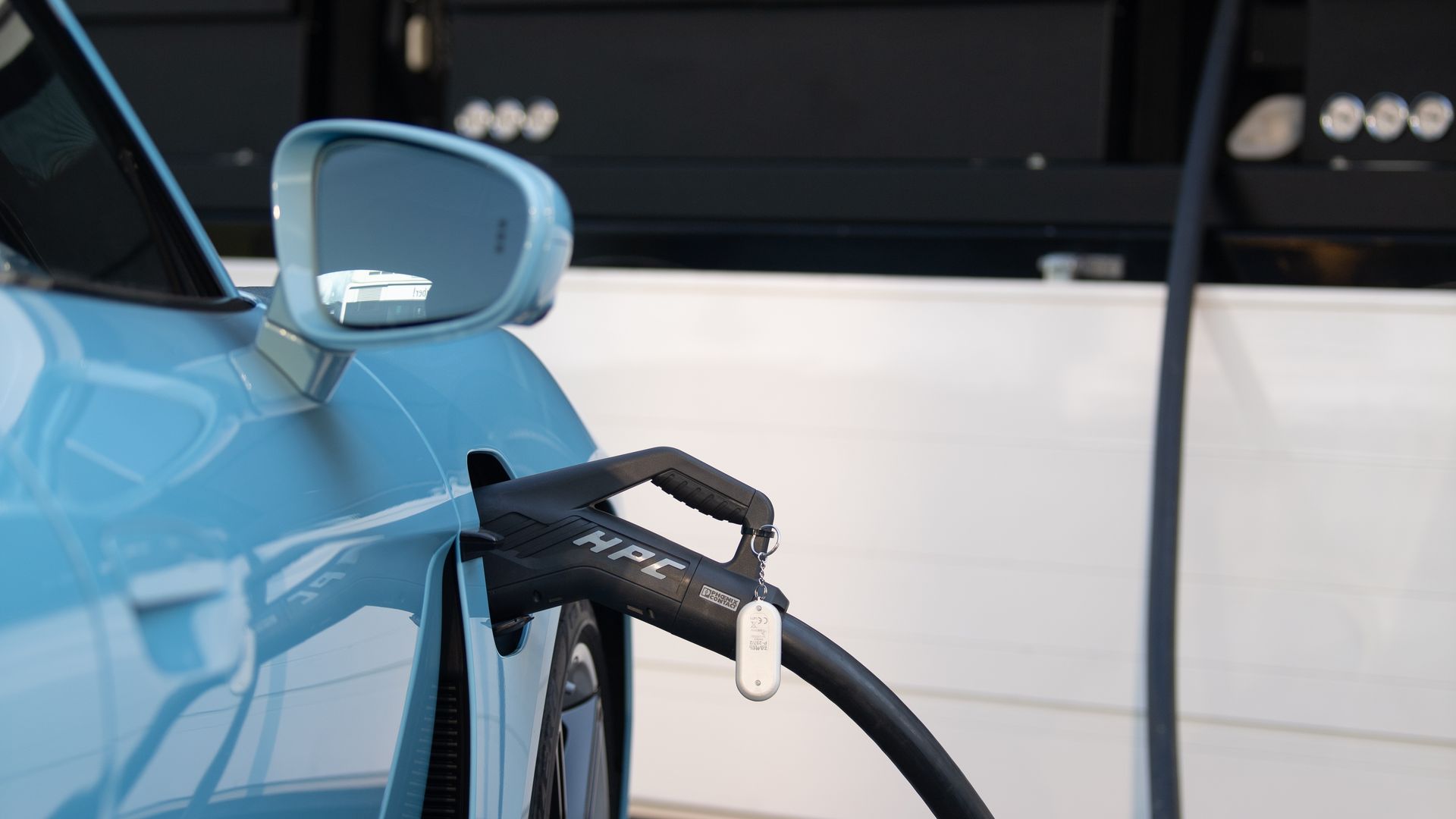 A blue electric vehicle is charged at a charging station