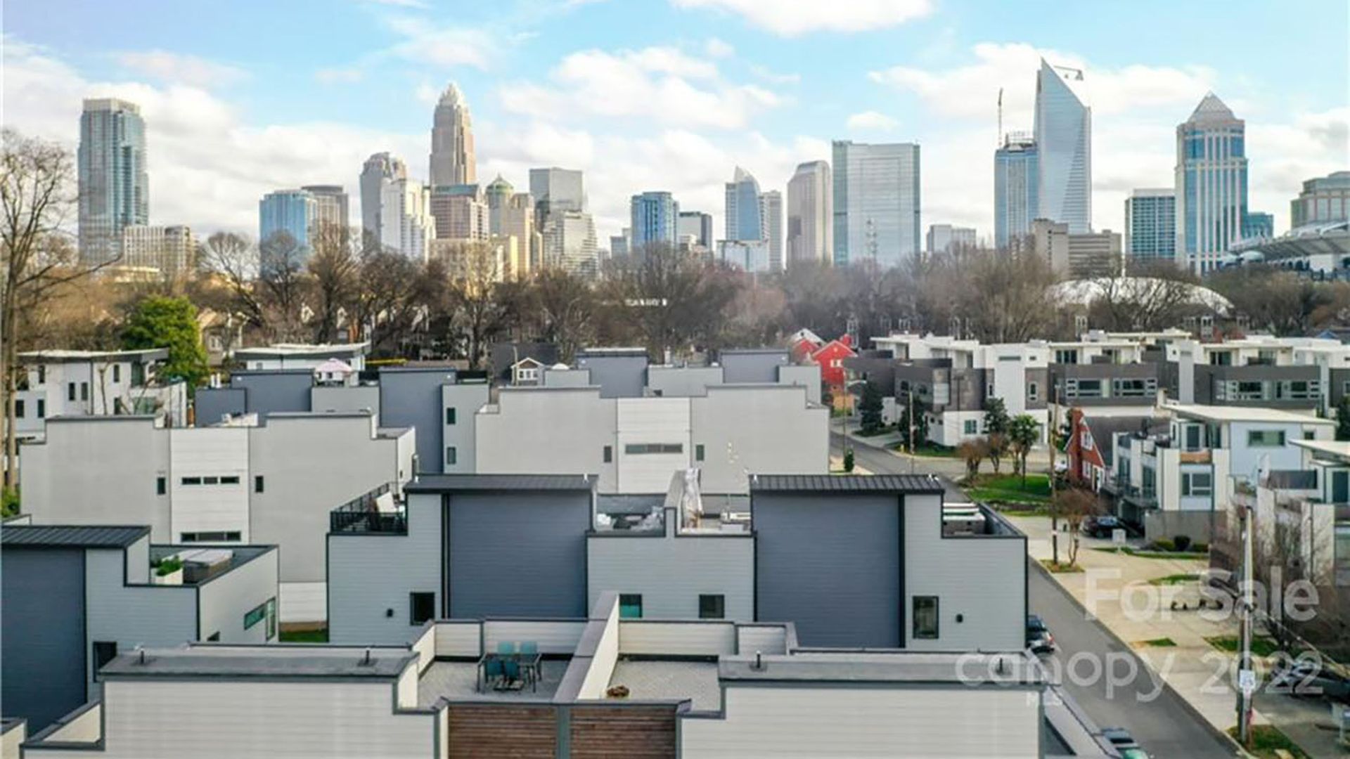 View of the Charlotte skyline from a rooftop. You can see several other rooftop patios from townhouses below.