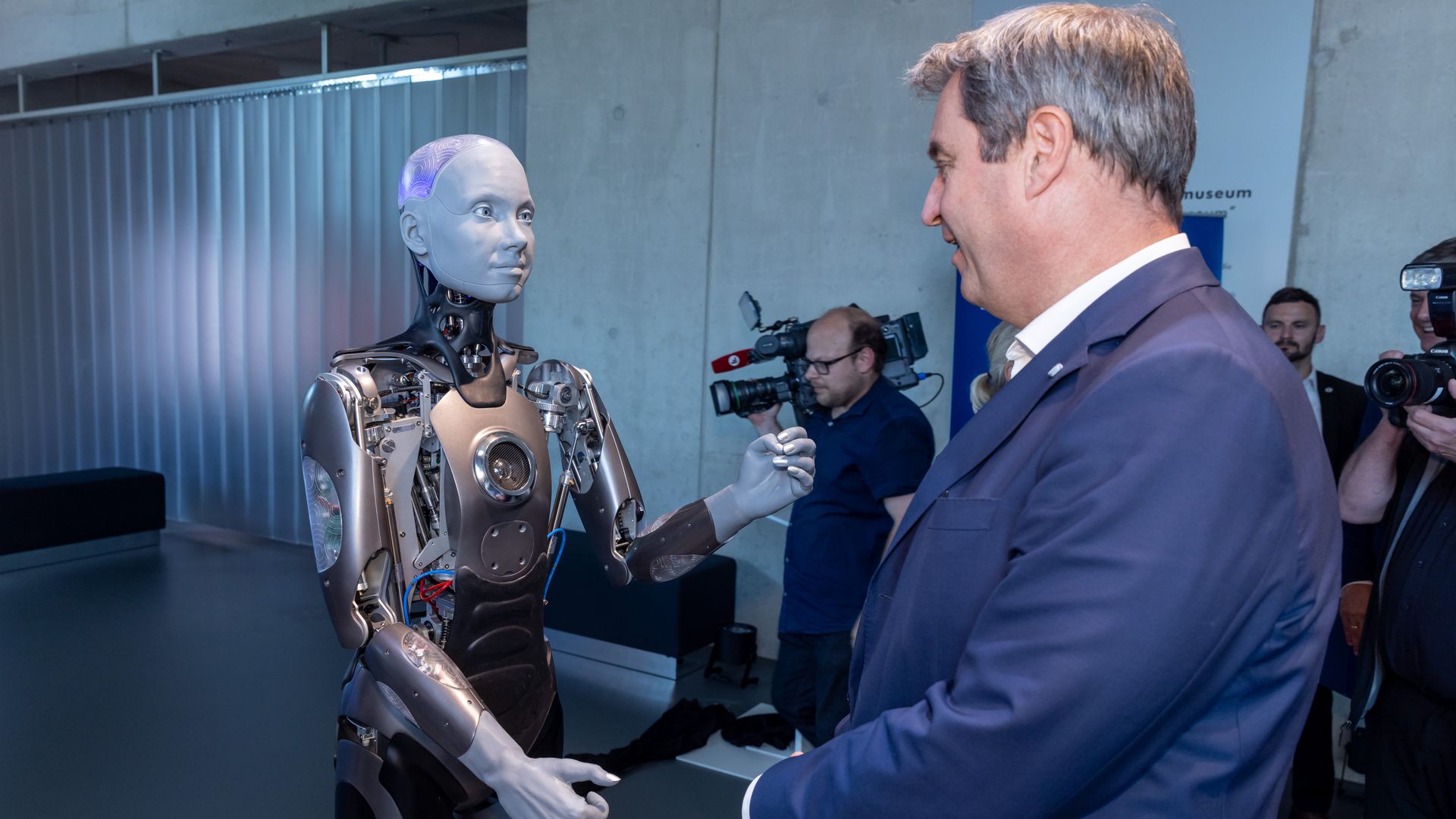 Ameca, a humsnoid robot, greets a Bavarian official.