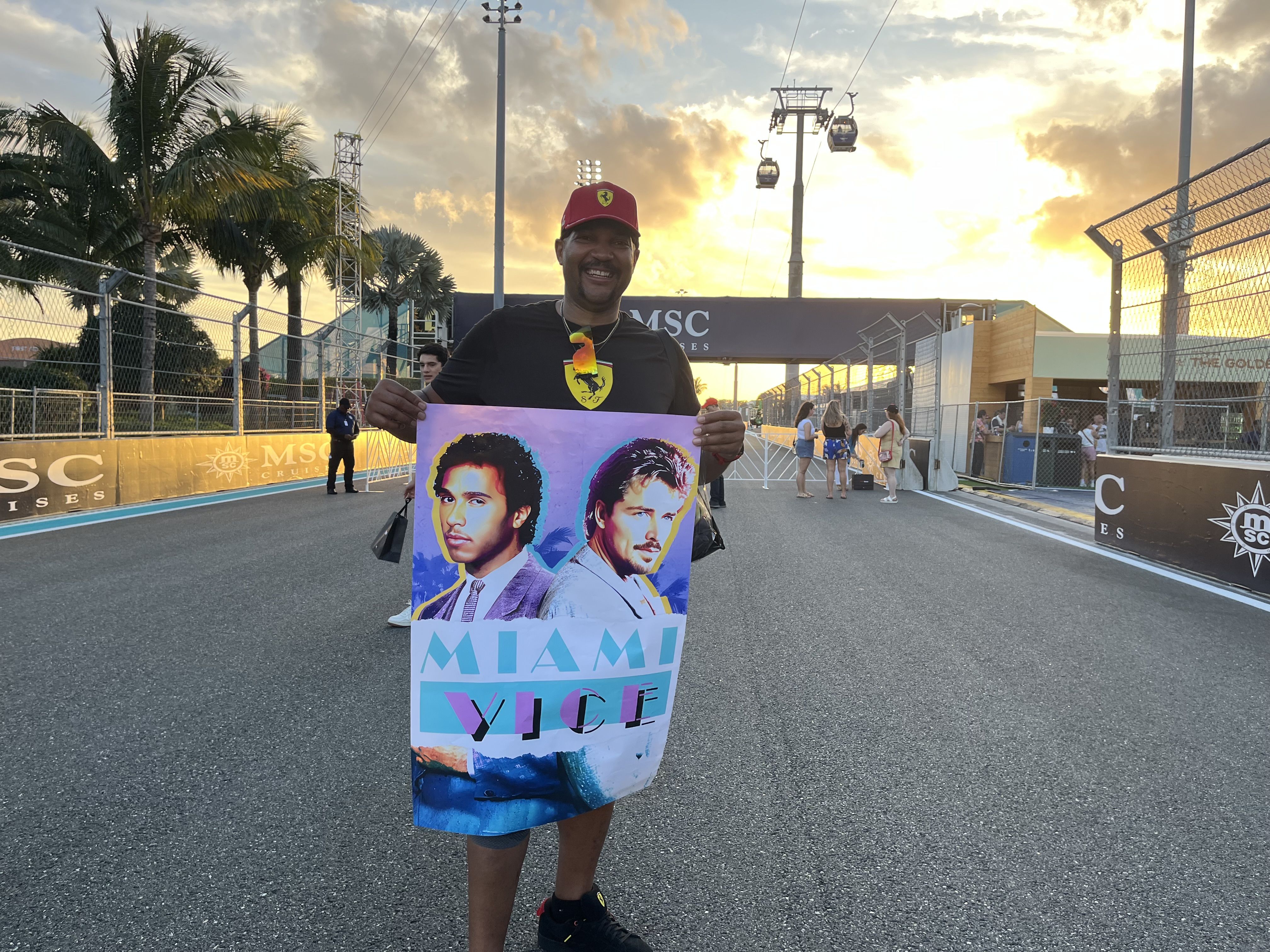 Ferrari fan at Miami Grand Prix with a "Miami Vice" poster showing both Ferrari drivers