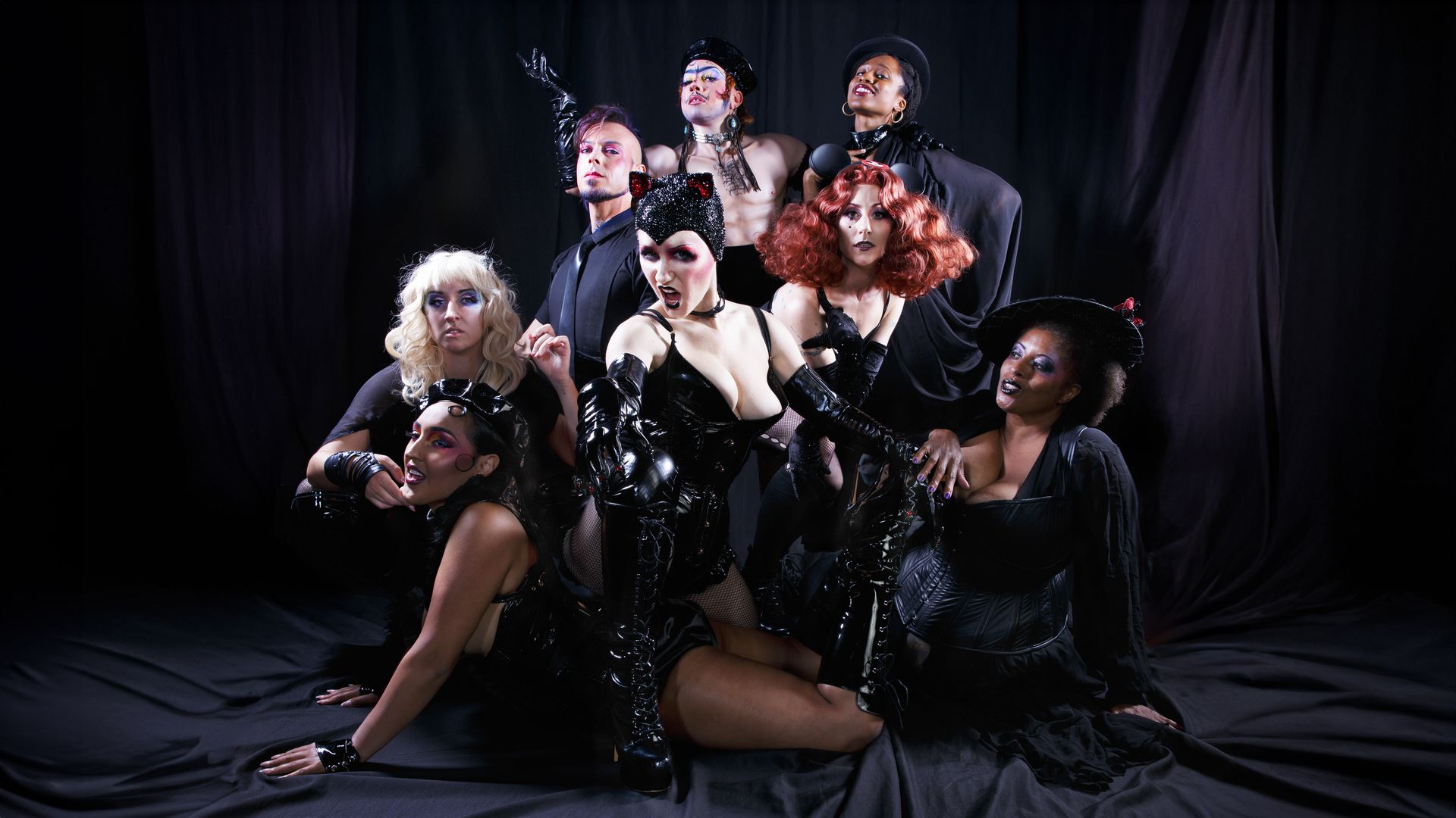 Photo of a group of performers dressed in black leather and costumes posing